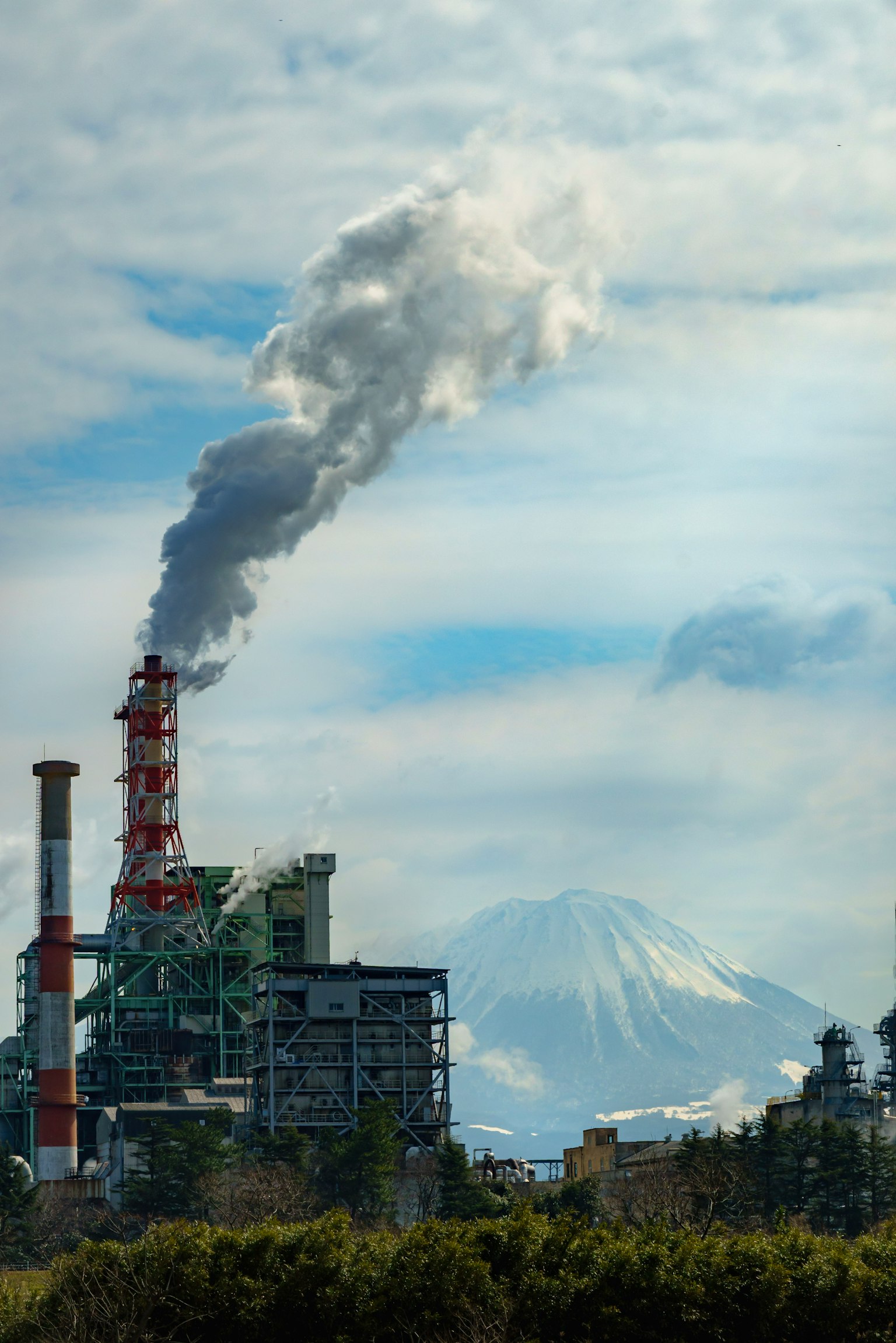 Usine émettant de la fumée avec une montagne au loin
