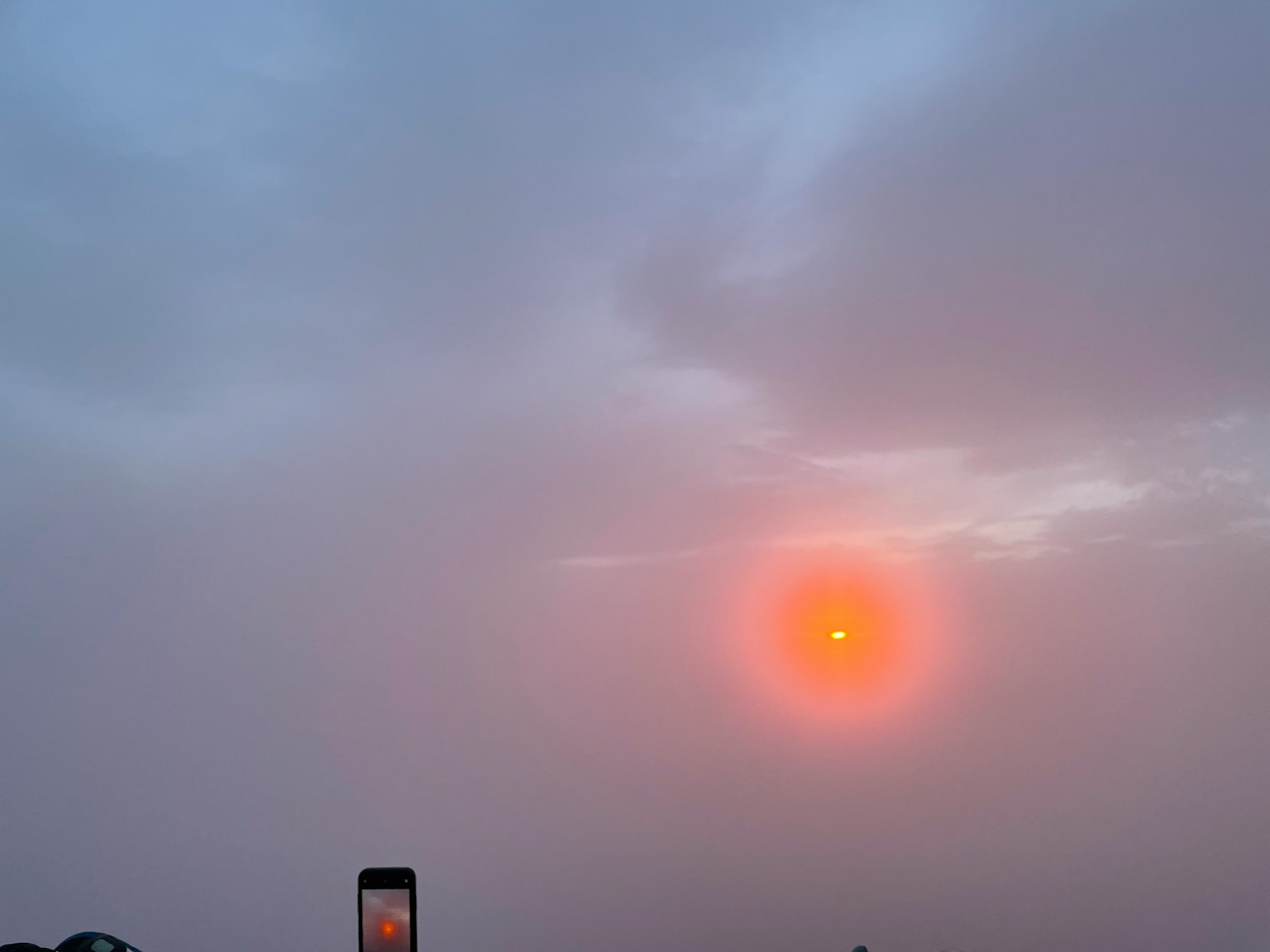 一幅橙色太陽透過多雲天空的場景