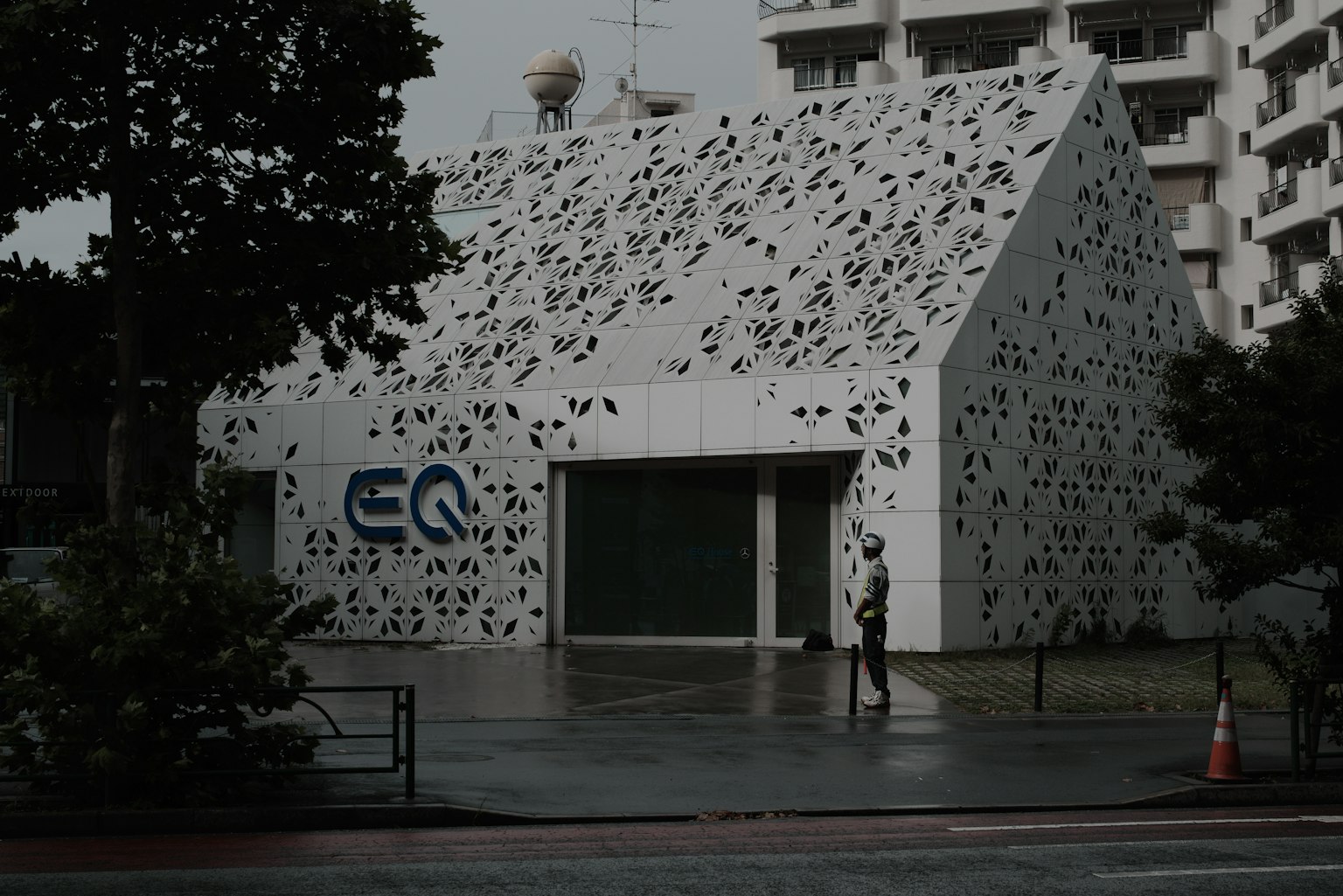 現代白色建築帶有EQ標誌獨特的穿孔設計在雨中走的人