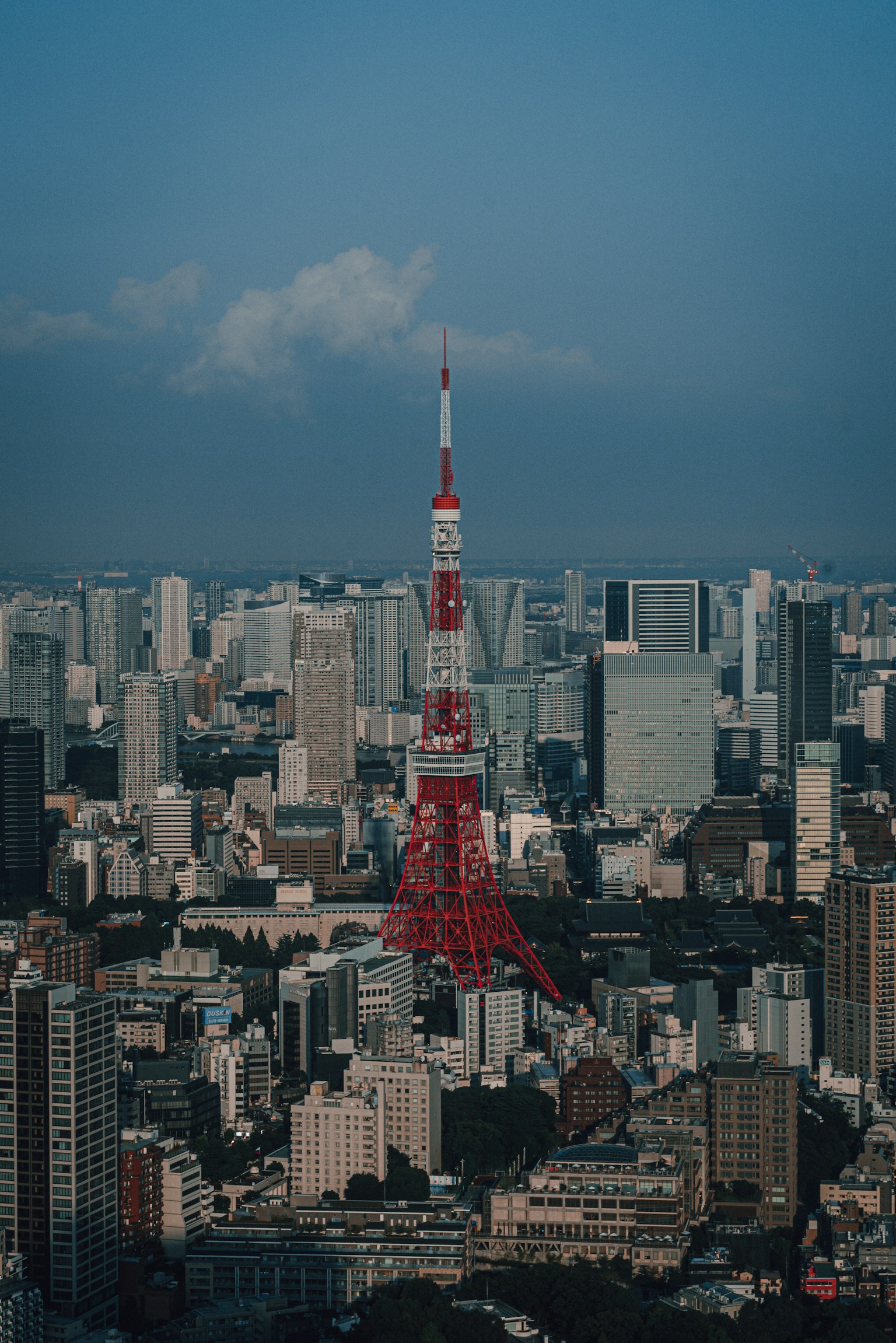 Menara Tokyo menjulang di antara gedung pencakar langit di bawah langit biru yang cerah