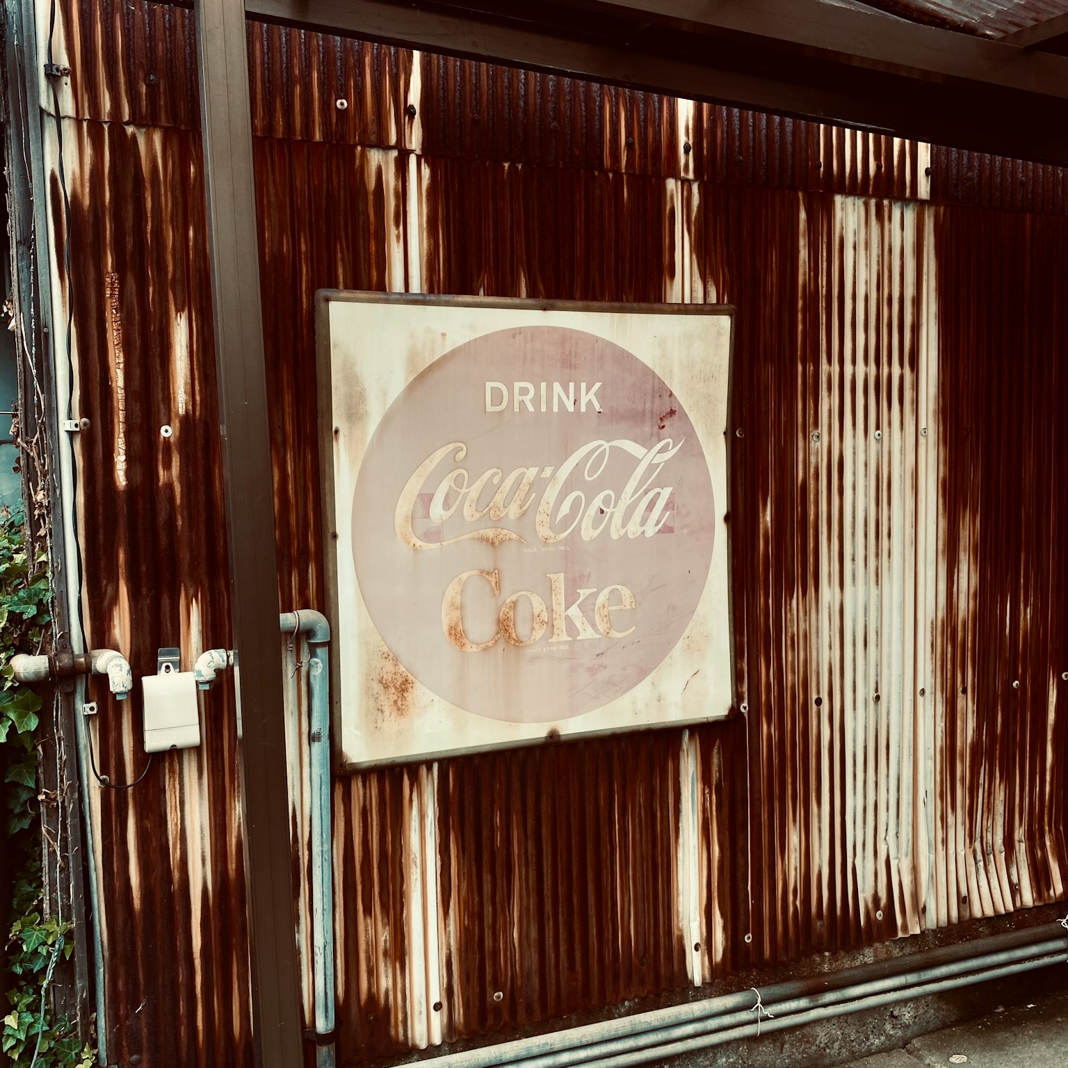 Faded Coca-Cola sign attached to an old wall