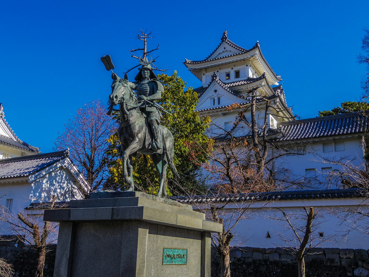 骑马武士的铜像，背景是樱花和城堡