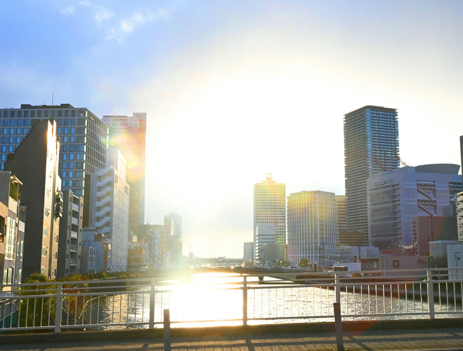 ทิวทัศน์เมืองที่มีอาคารทันสมัยสะท้อนแสงพระอาทิตย์ตกบนแม่น้ำ