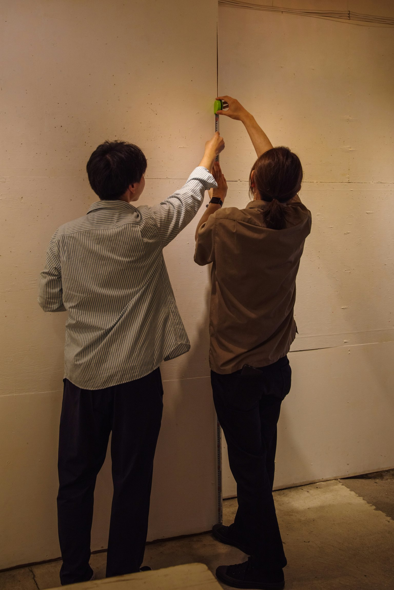 Two people installing a white board on a wall