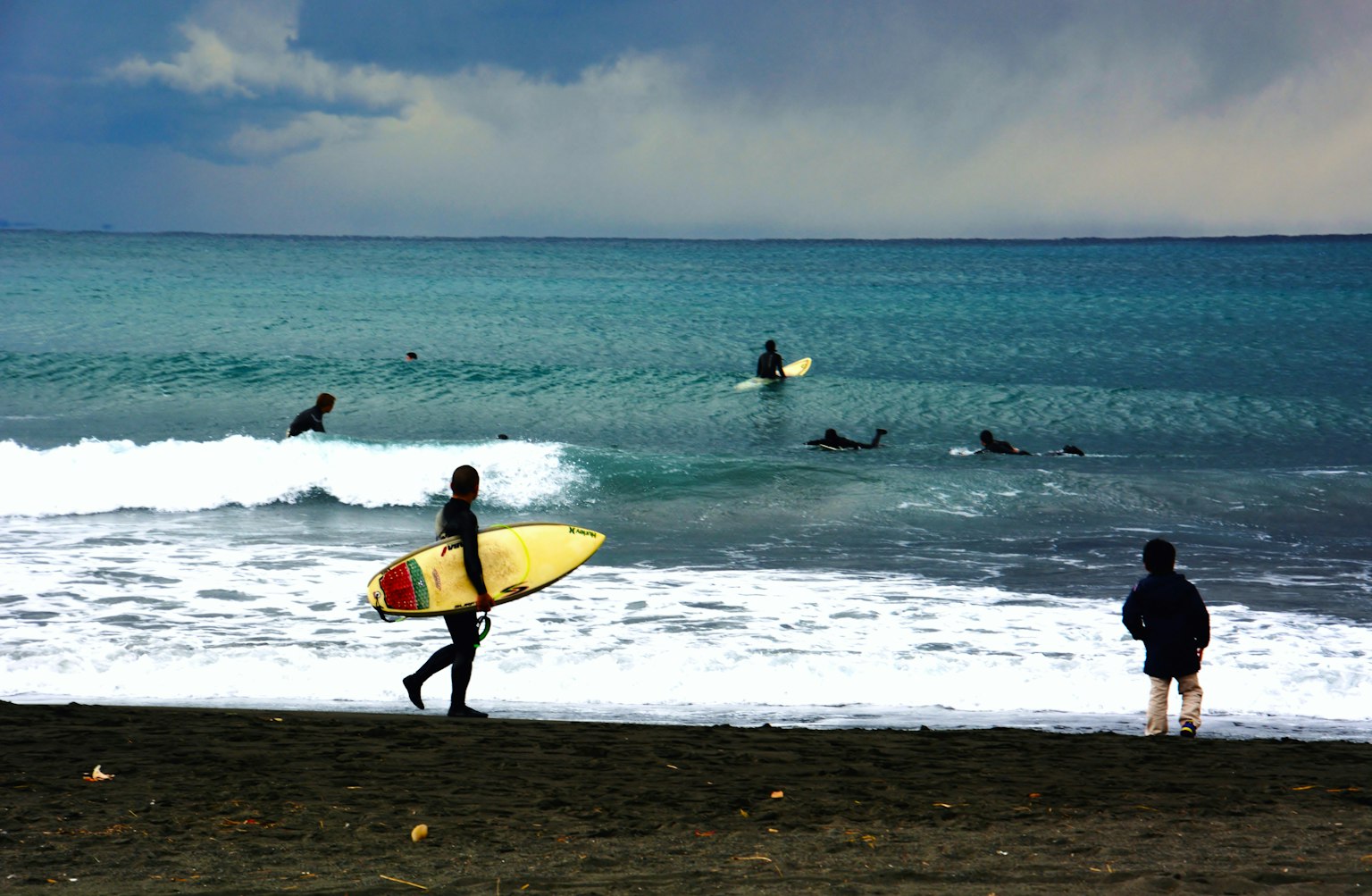 Bild, das Surfer und eine Strandlandschaft zeigt