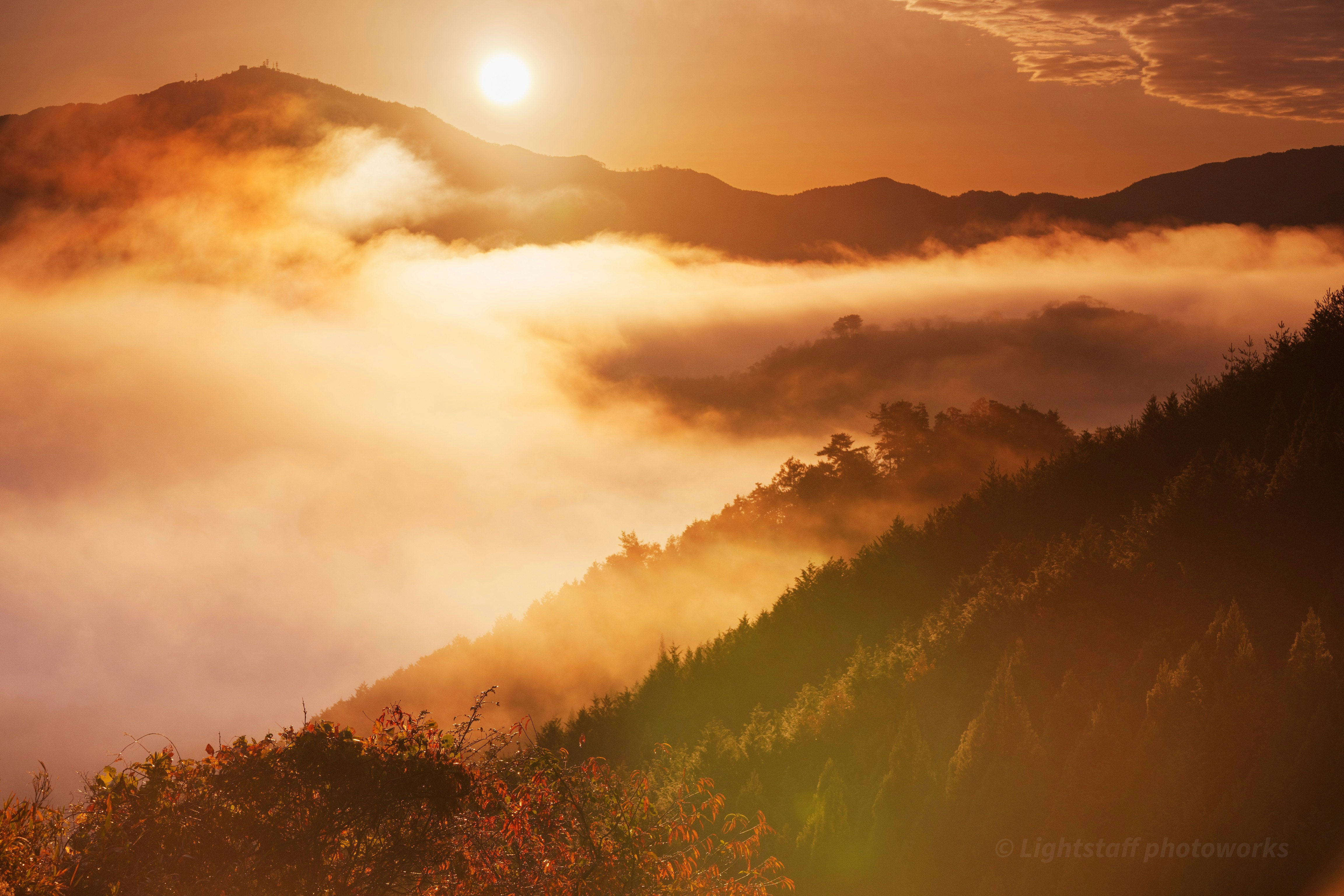 雲海と紅葉の広がる山並みと朝日