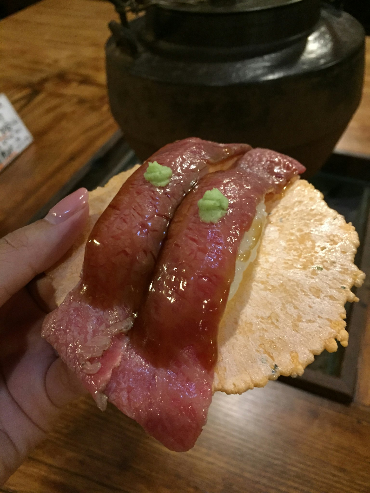脆米上放着两片肉和绿色芥末的寿司