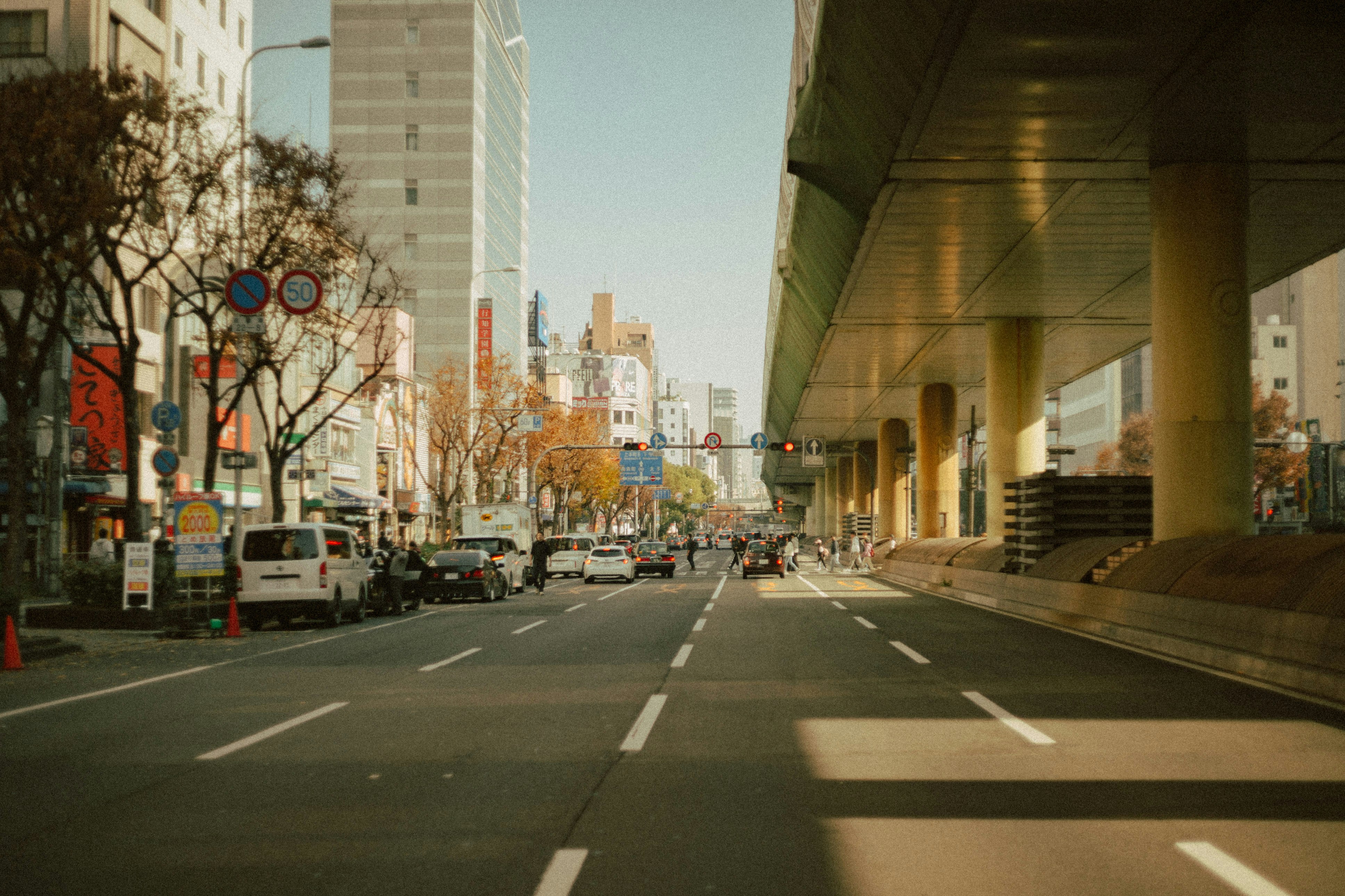 Voitures sur une large route sous une structure surélevée avec skyline urbaine