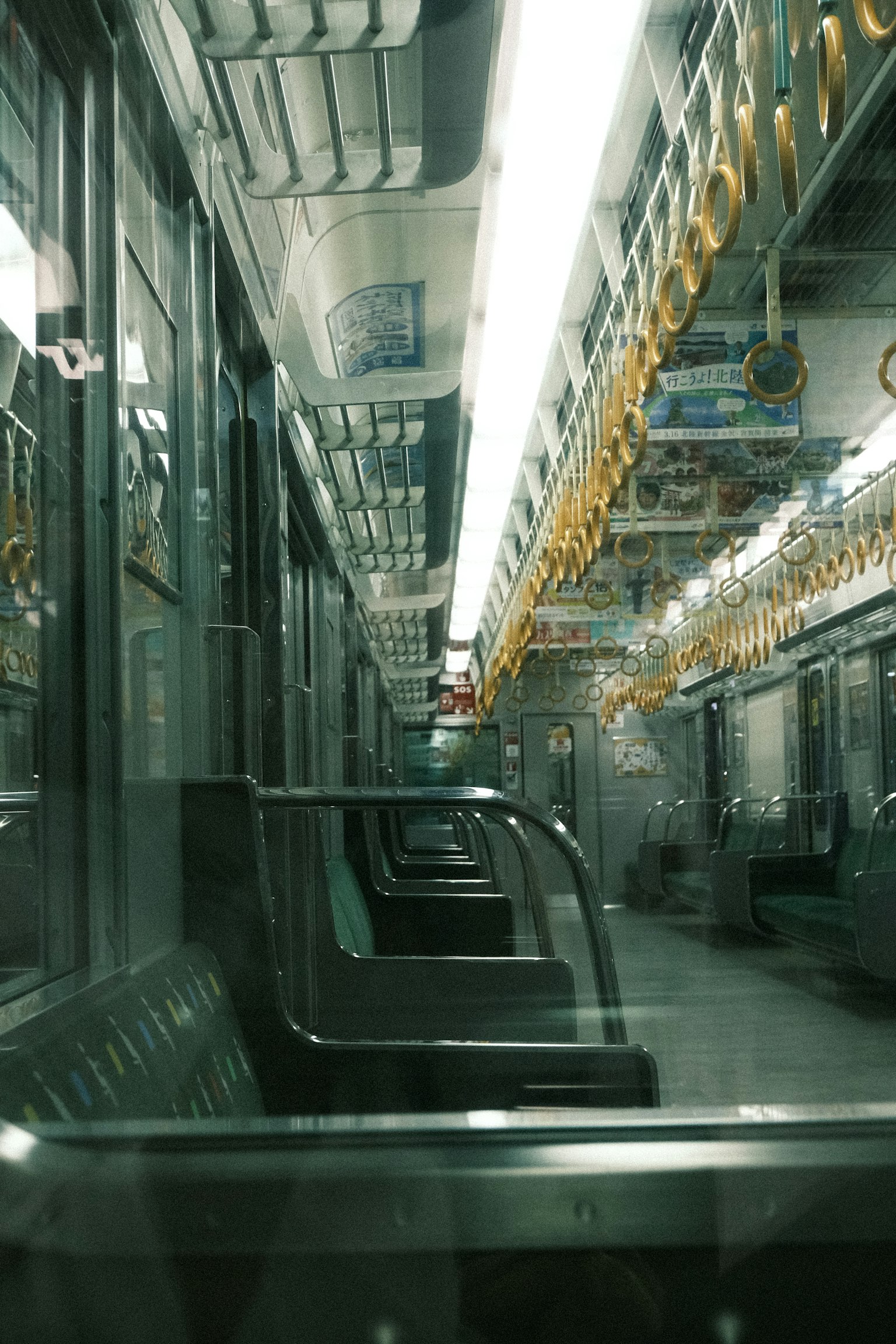 Interior of an empty subway train long seats and hanging straps visible