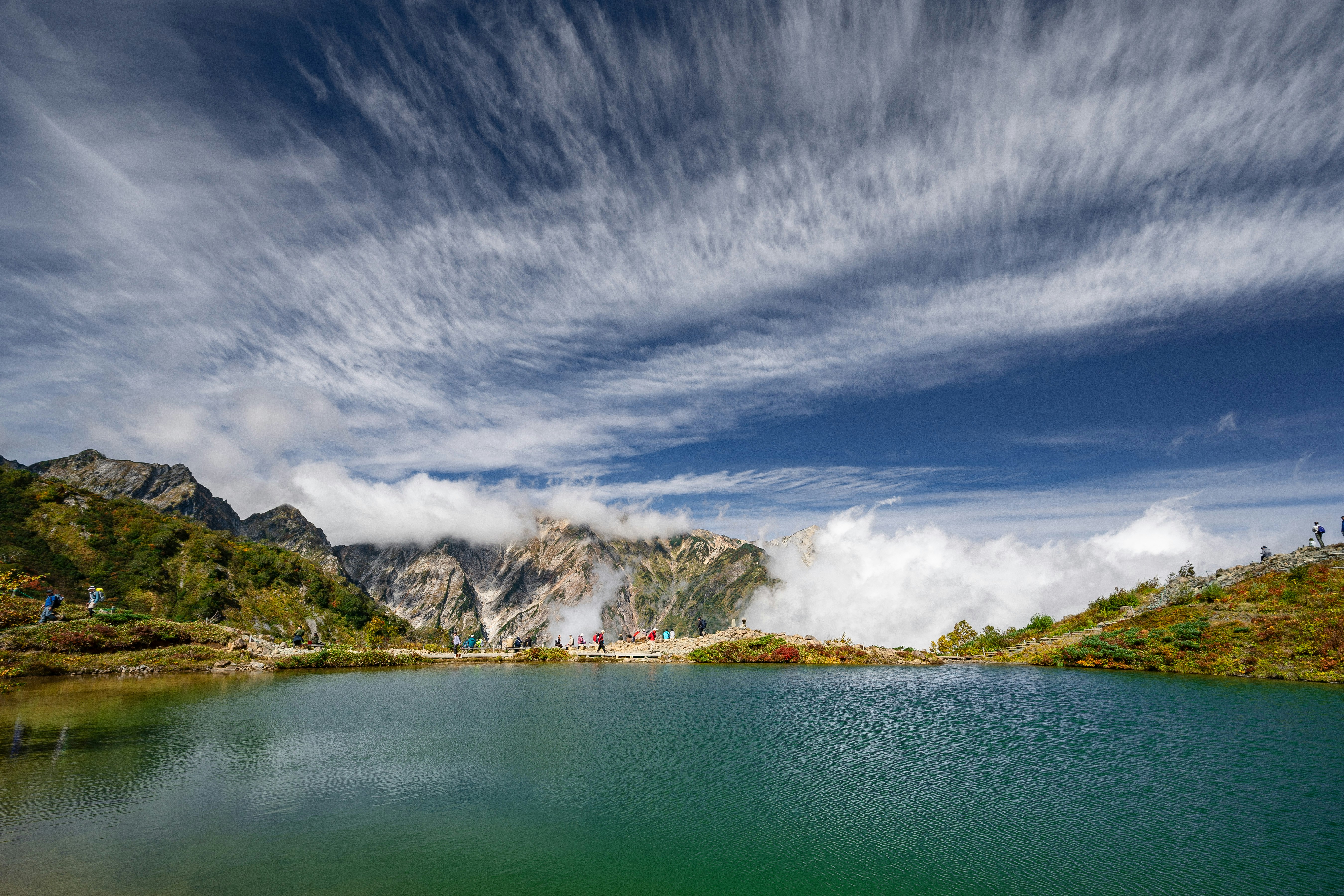八方池の静かな湖面と白馬連峰を望む登山風景
