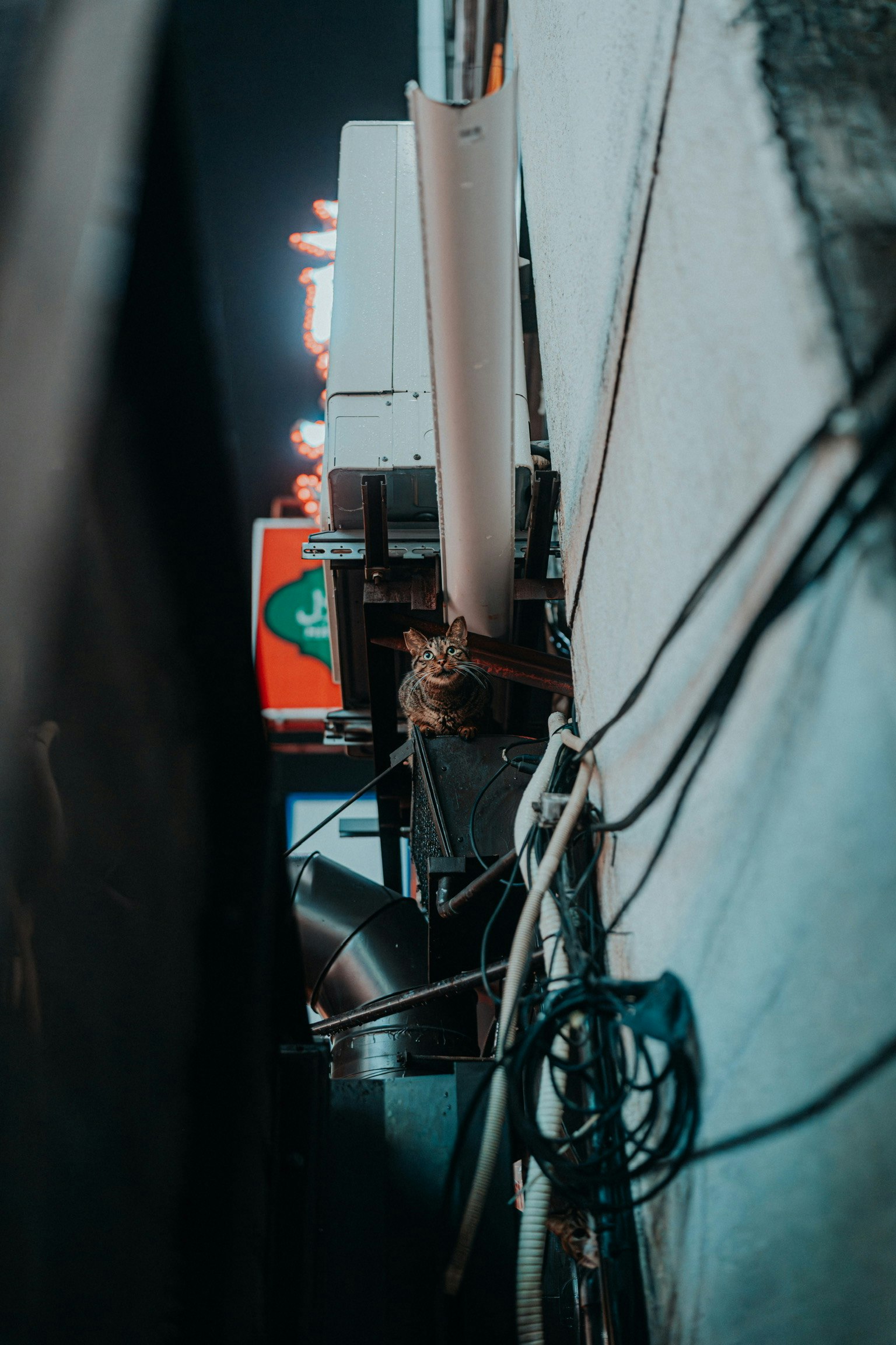 Close-up shot of wires and equipment along a wall in a nighttime urban setting