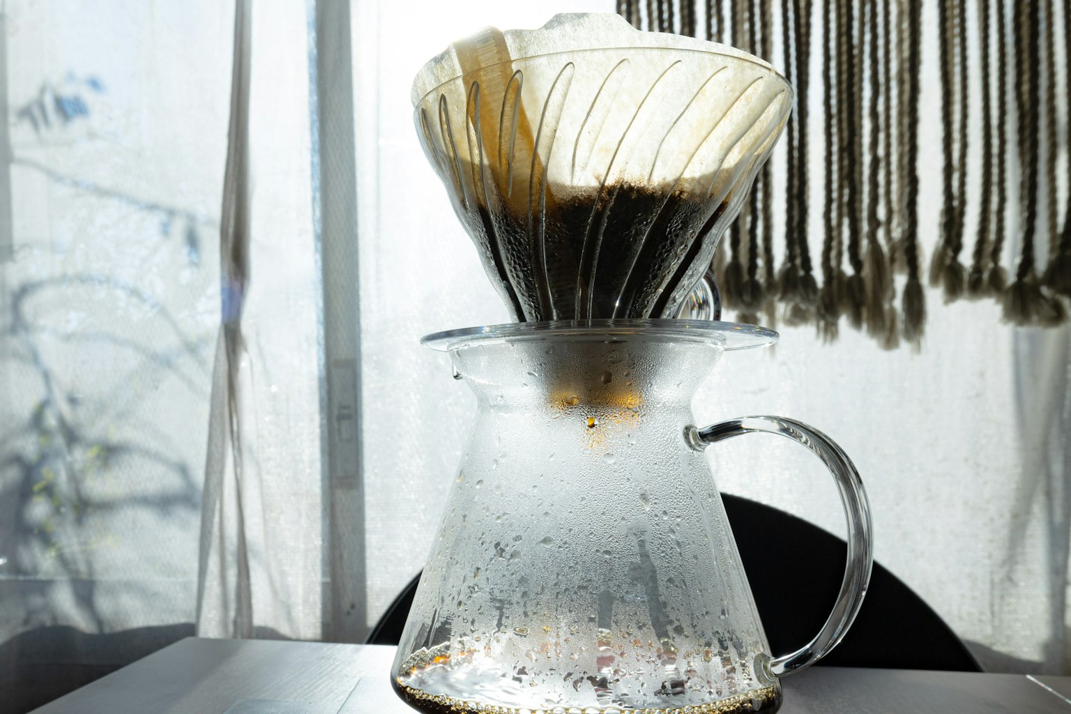 Coffee dripper and server in sunlight with condensation