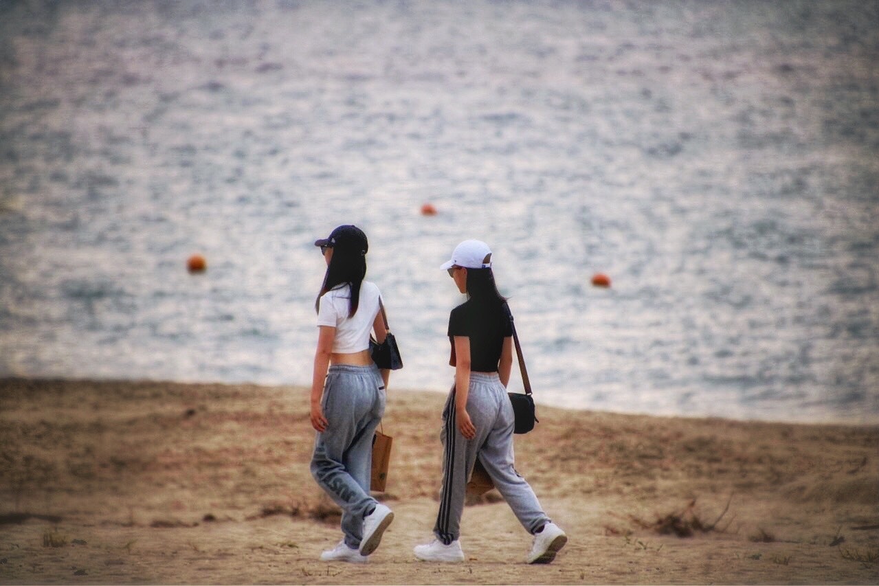 日本海の夏の浜辺を歩く女子二人組