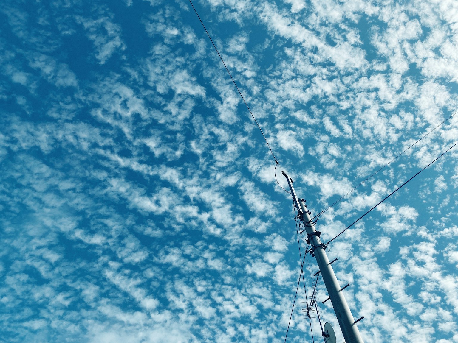 Blue sky filled with white clouds and a tall antenna