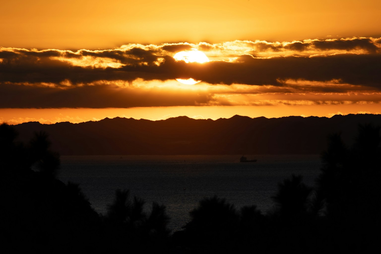 Impresionante atardecer sobre montañas con siluetas de árboles