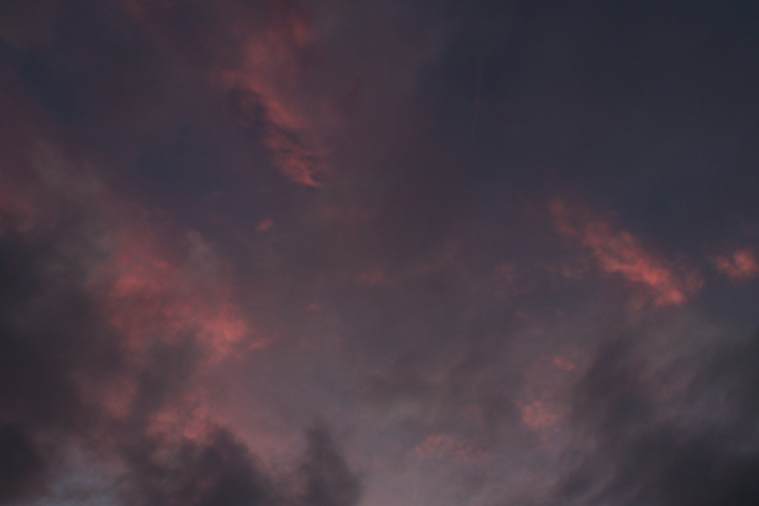 Dunkle Wolken, die von roten Tönen beim Sonnenuntergang beleuchtet werden