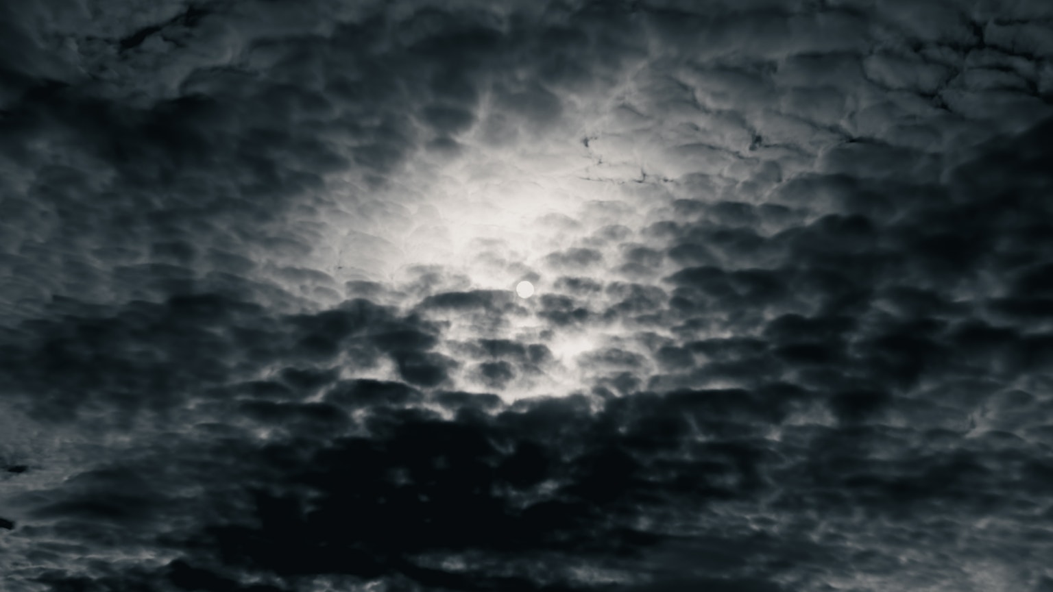 Bright light shining through dark clouds in the sky