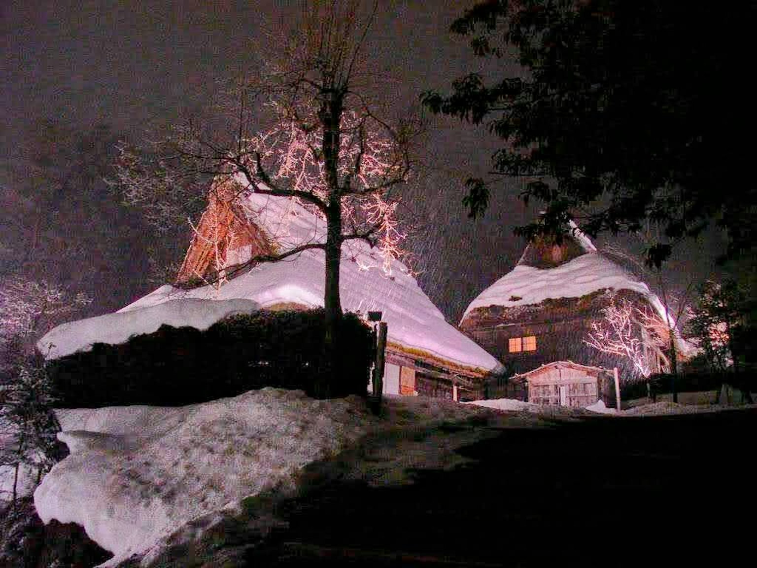 Scena notturna di case giapponesi tradizionali coperte di neve