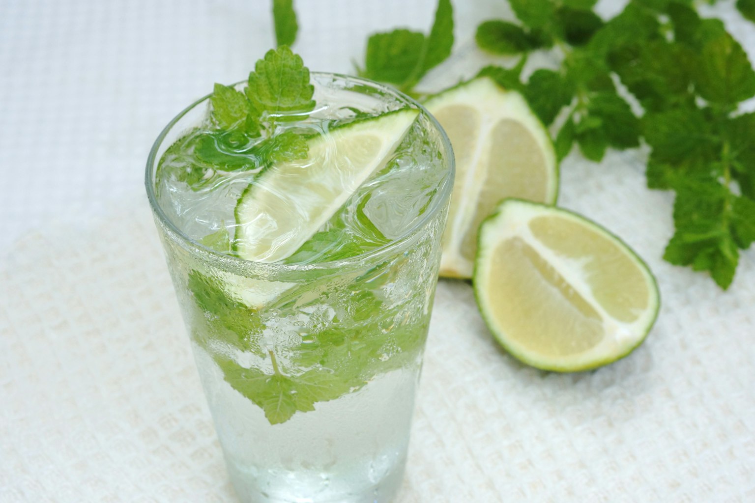 A glass of refreshing drink with mint and lime slices