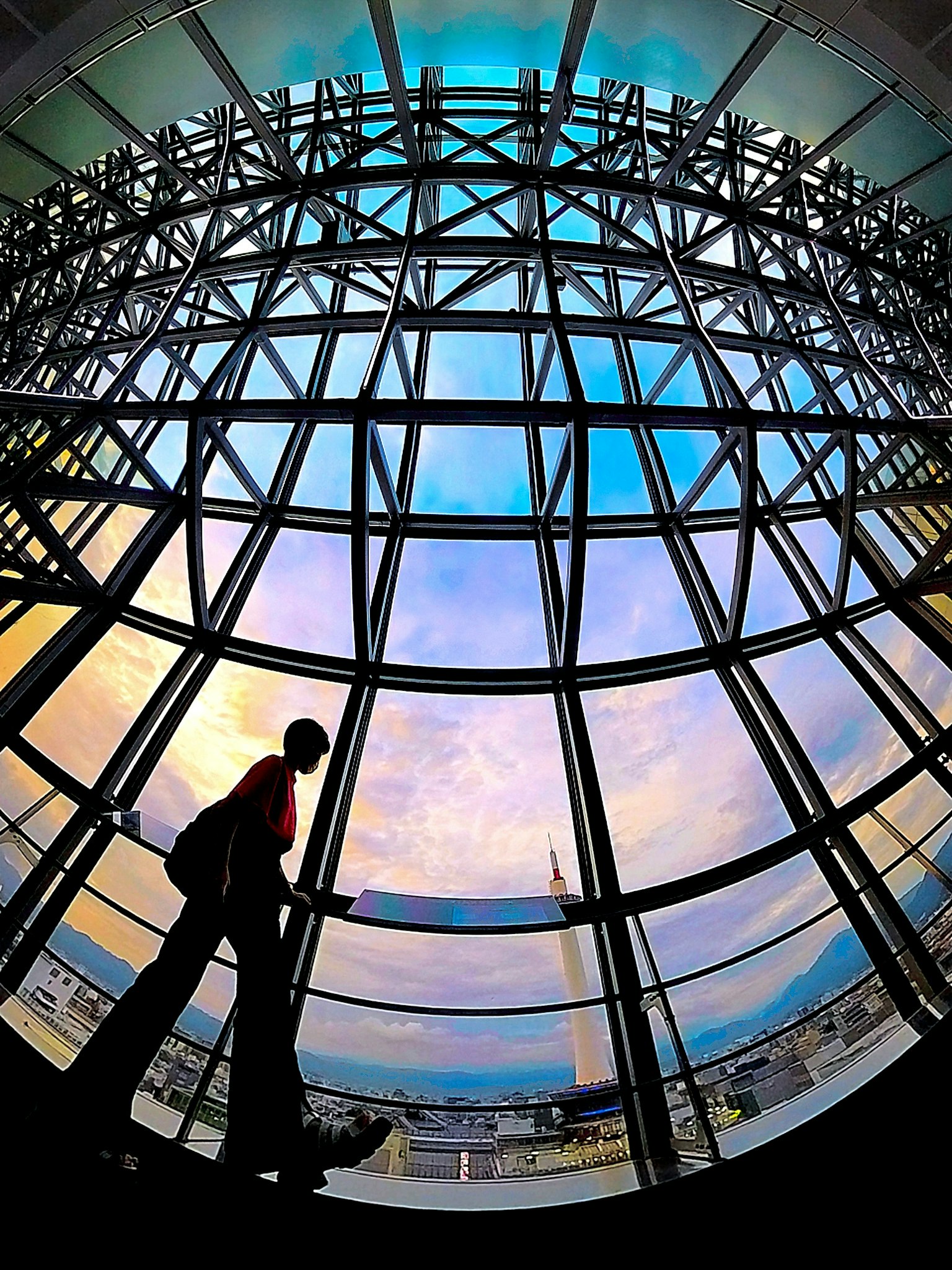 Silueta de una persona mirando por una ventana grande con un cielo colorido