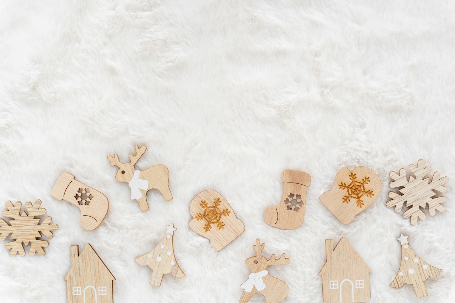Un set di ornamenti di Natale in legno disposti su uno sfondo in pelliccia bianca