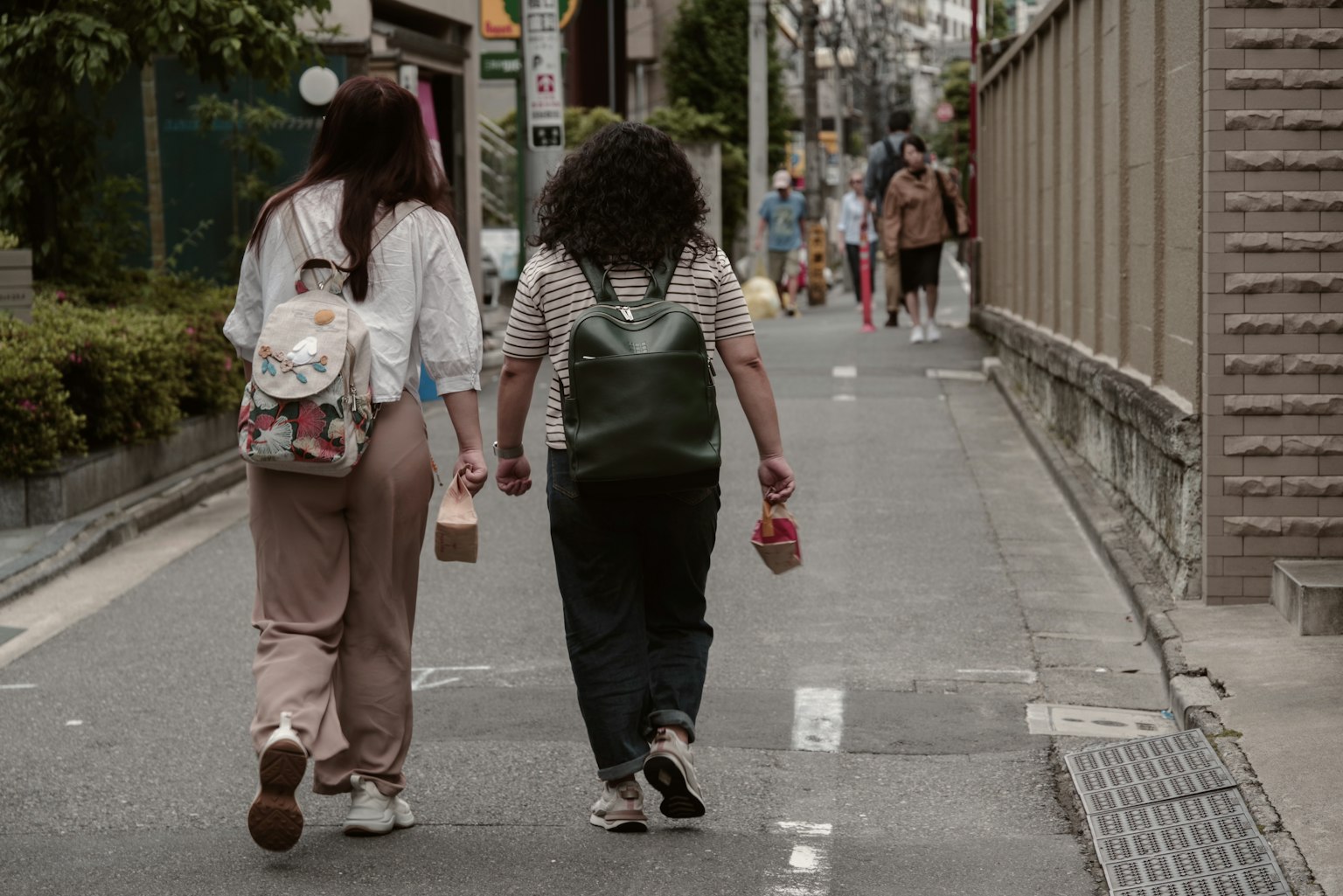 Zwei Frauen, die Hand in Hand auf einer Stadtstraße gehen