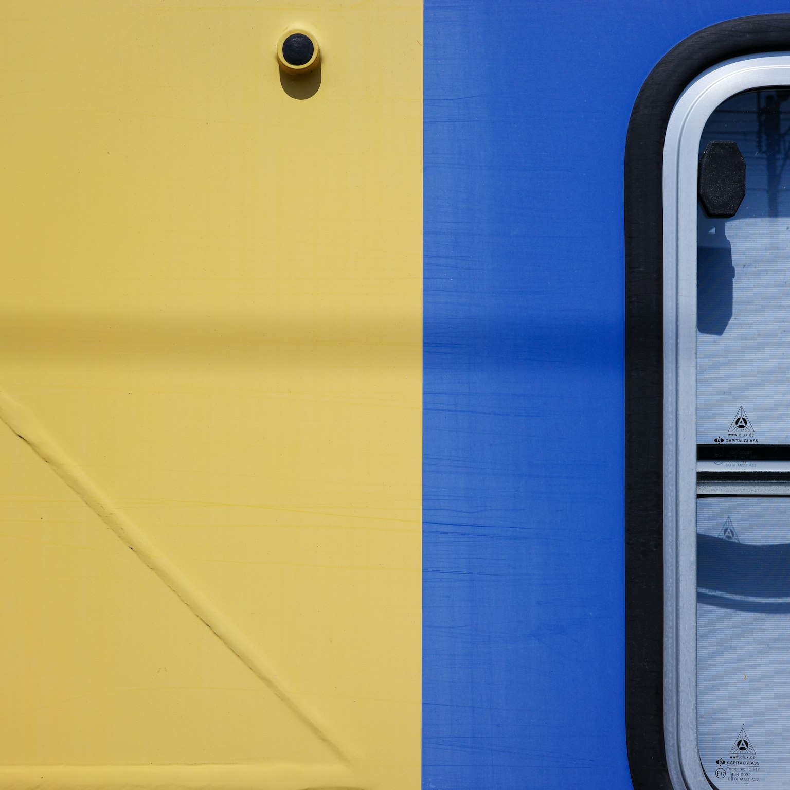 Vista laterale di un treno con colori giallo e blu e una finestra