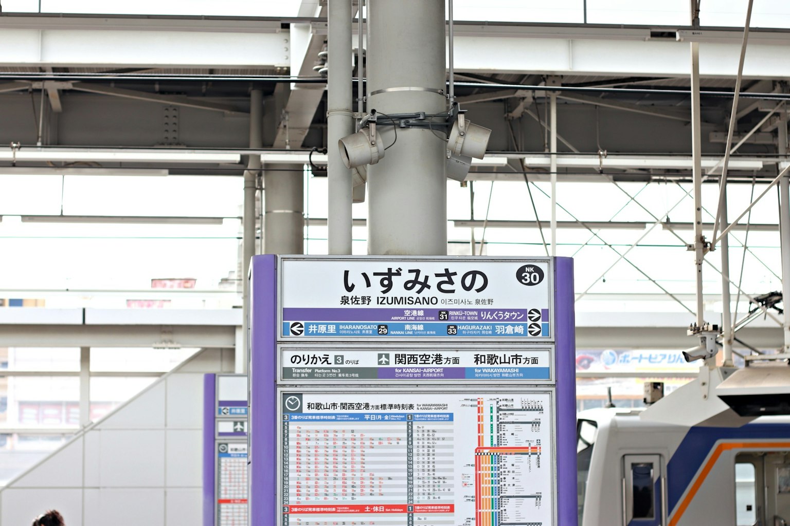 Informationsschild an der Station Izumisano mit Zug
