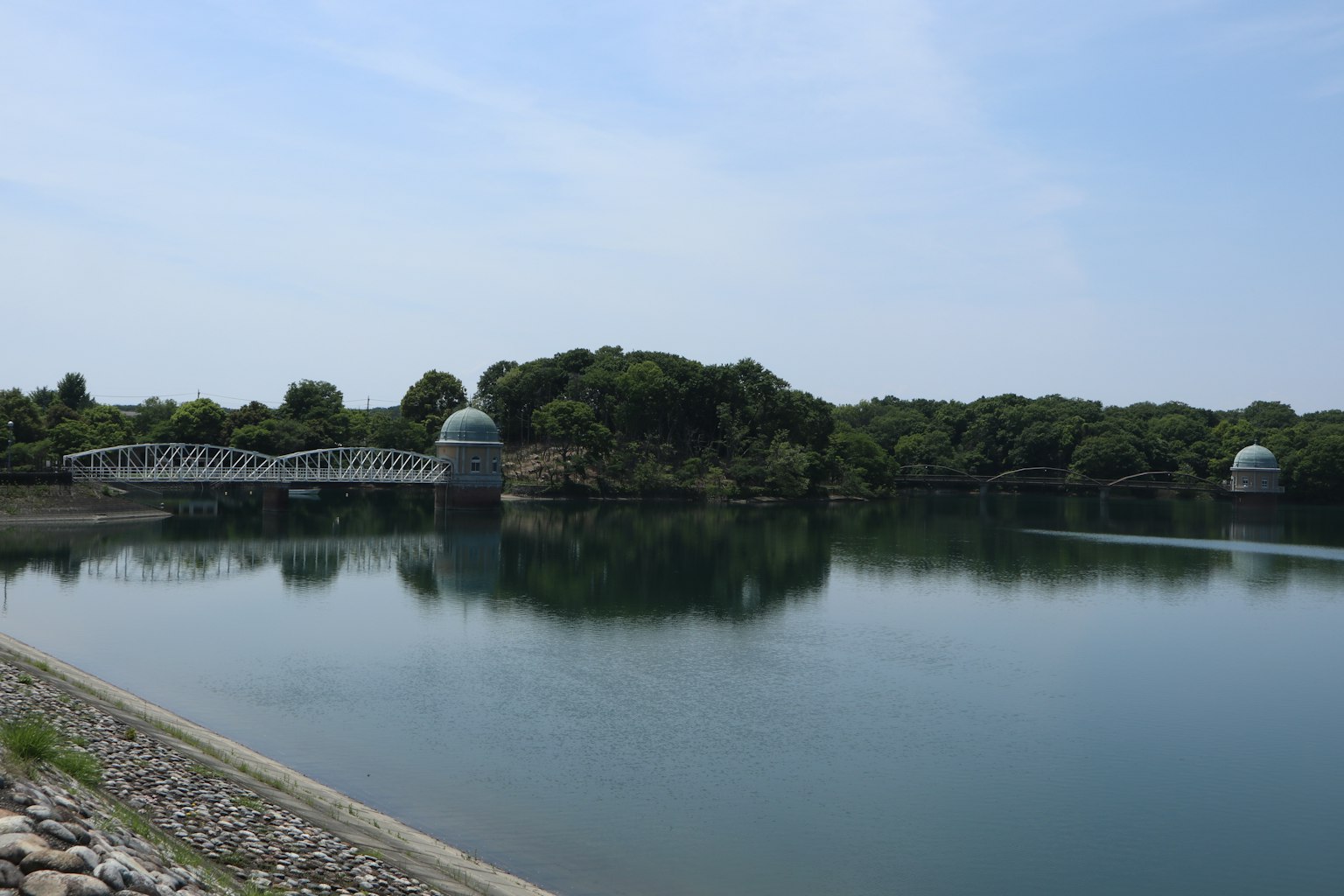 Lago calmo con rive verdi e due strutture a forma di cupola