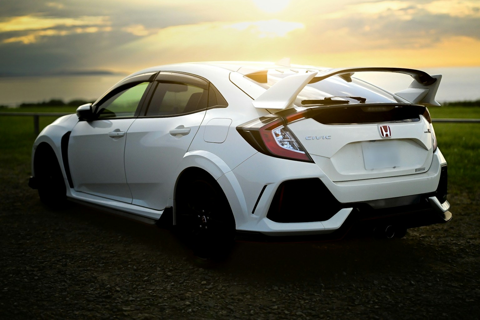 Voiture Honda blanche garée avec le coucher de soleil en arrière-plan mettant en valeur un design sportif