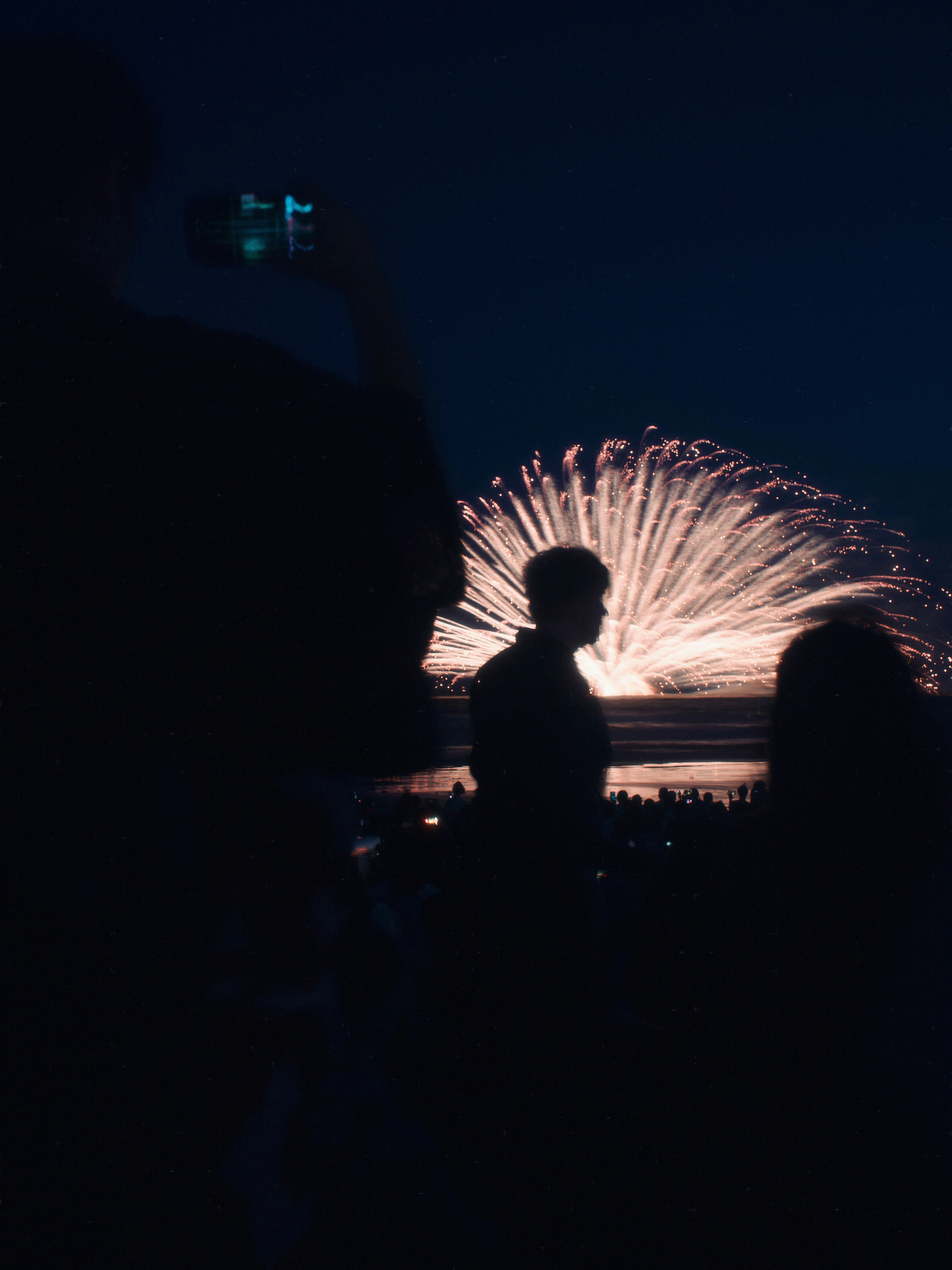 花火大会の夜、打ち上がる大輪の花火と観客のシルエット