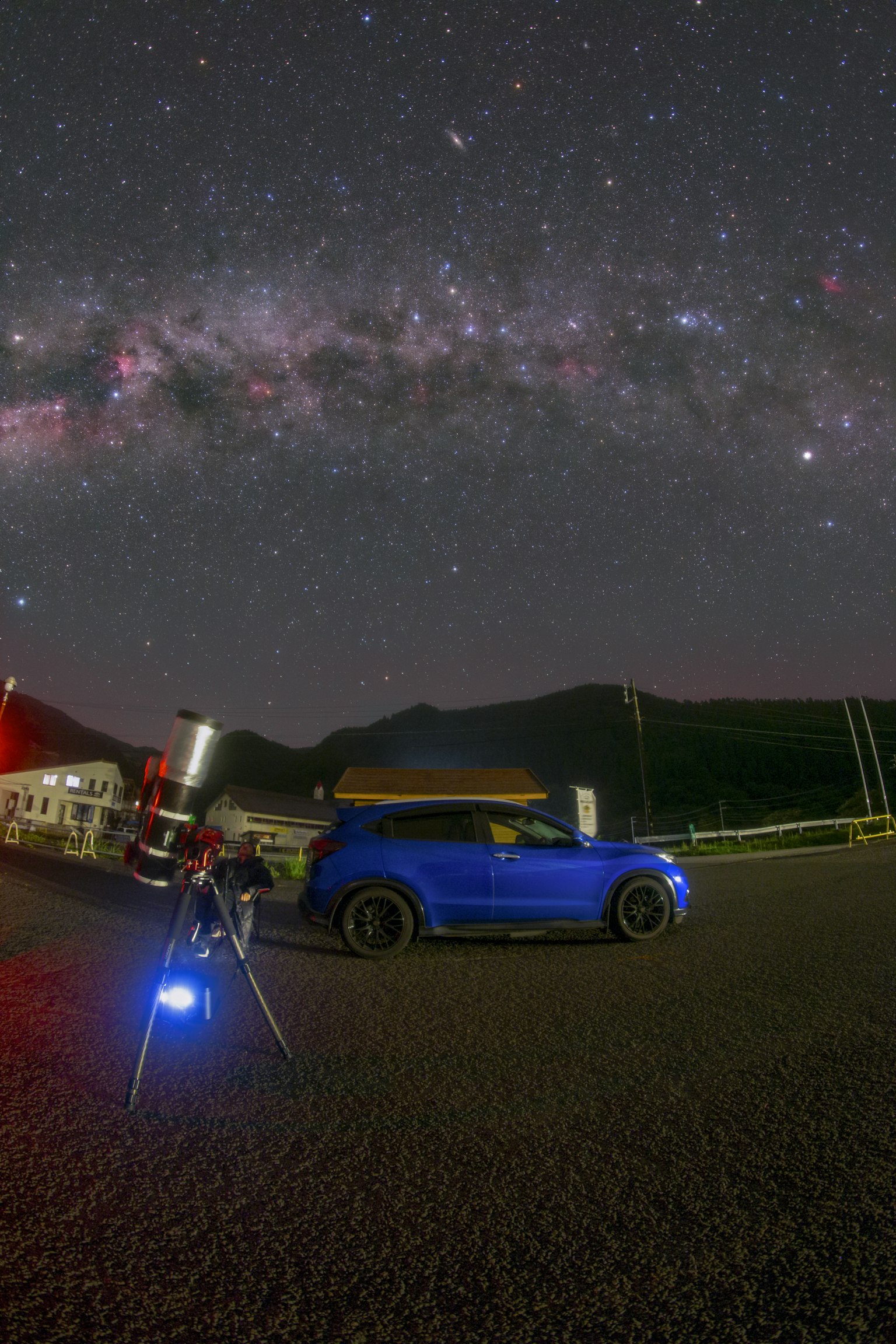Ein blauer Wagen und ein Teleskop unter einem Sternenhimmel