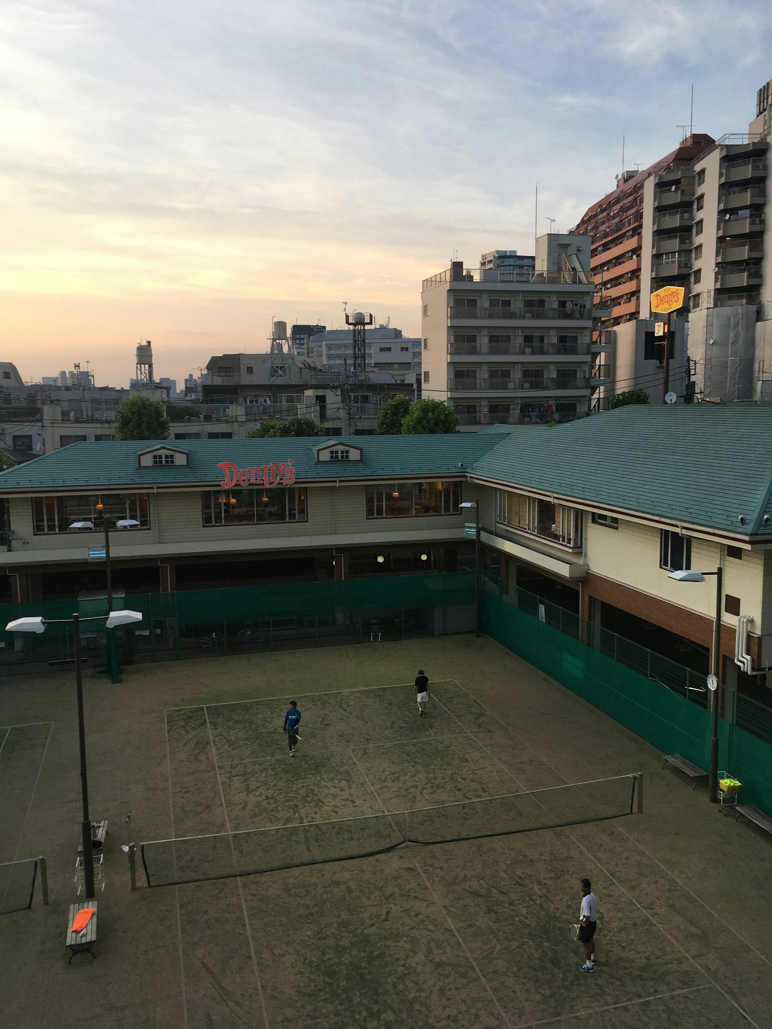 Spieler, die bei Sonnenuntergang auf einem Tennisplatz spielen
