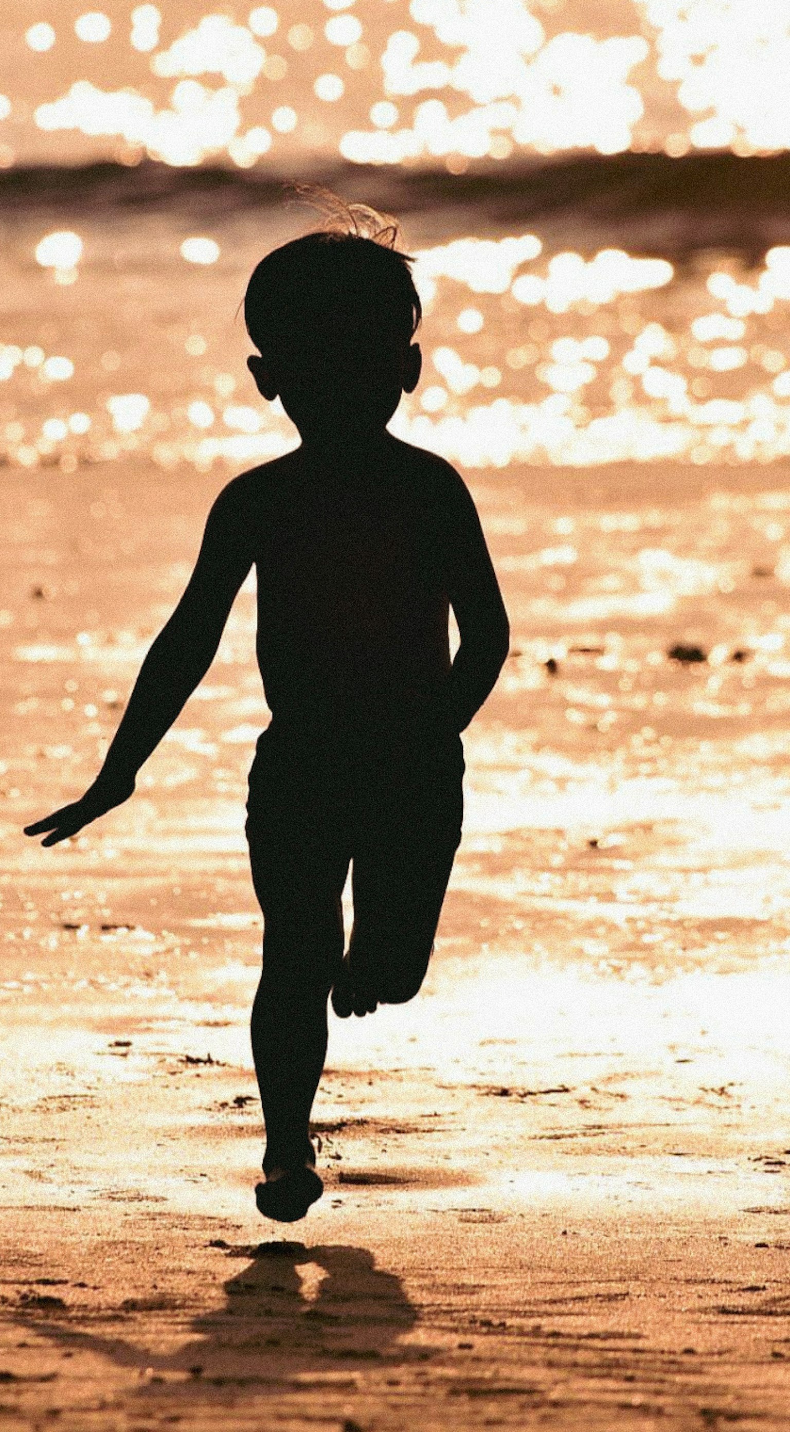 Silhouette di un bambino che corre nella luce del tramonto