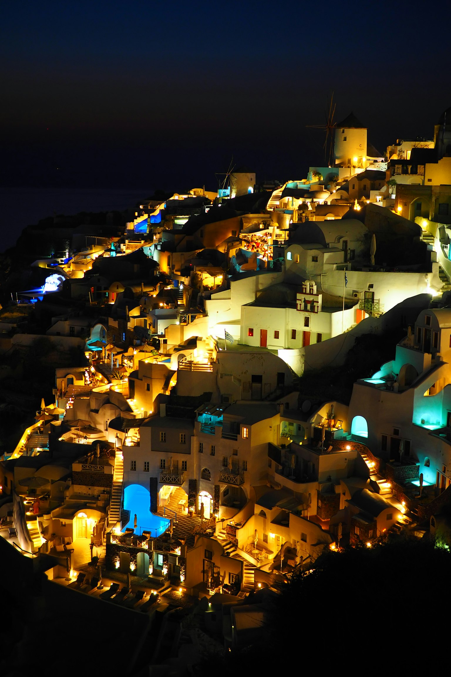 Khung cảnh đêm đẹp của Santorini với các tòa nhà trắng sáng và biển xanh
