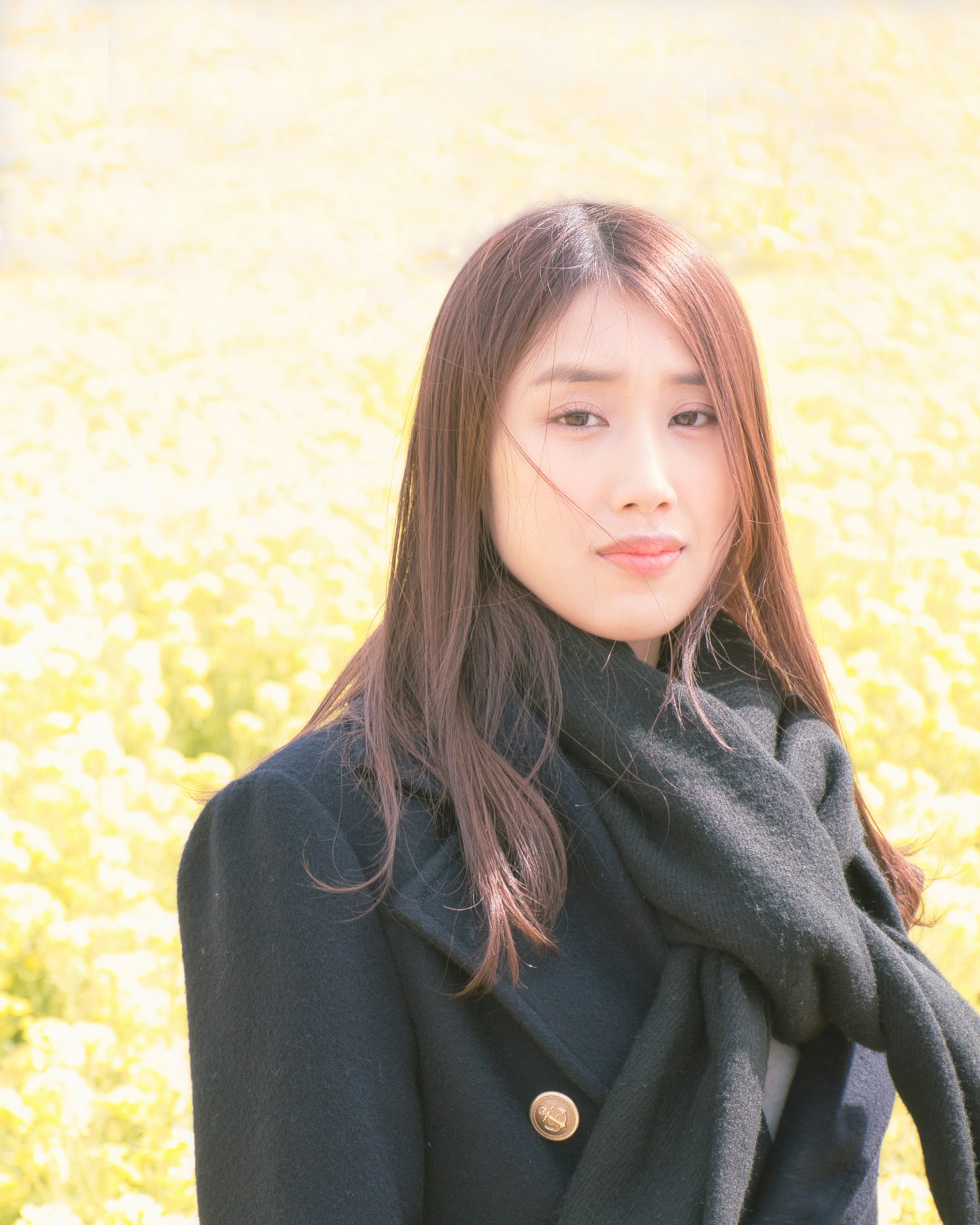 Portrait of a woman standing in front of a yellow flower field