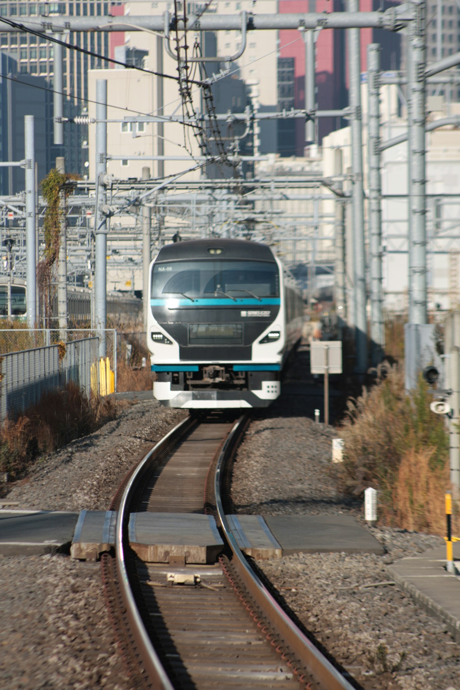 Un treno moderno che si avvicina su binari in un contesto urbano