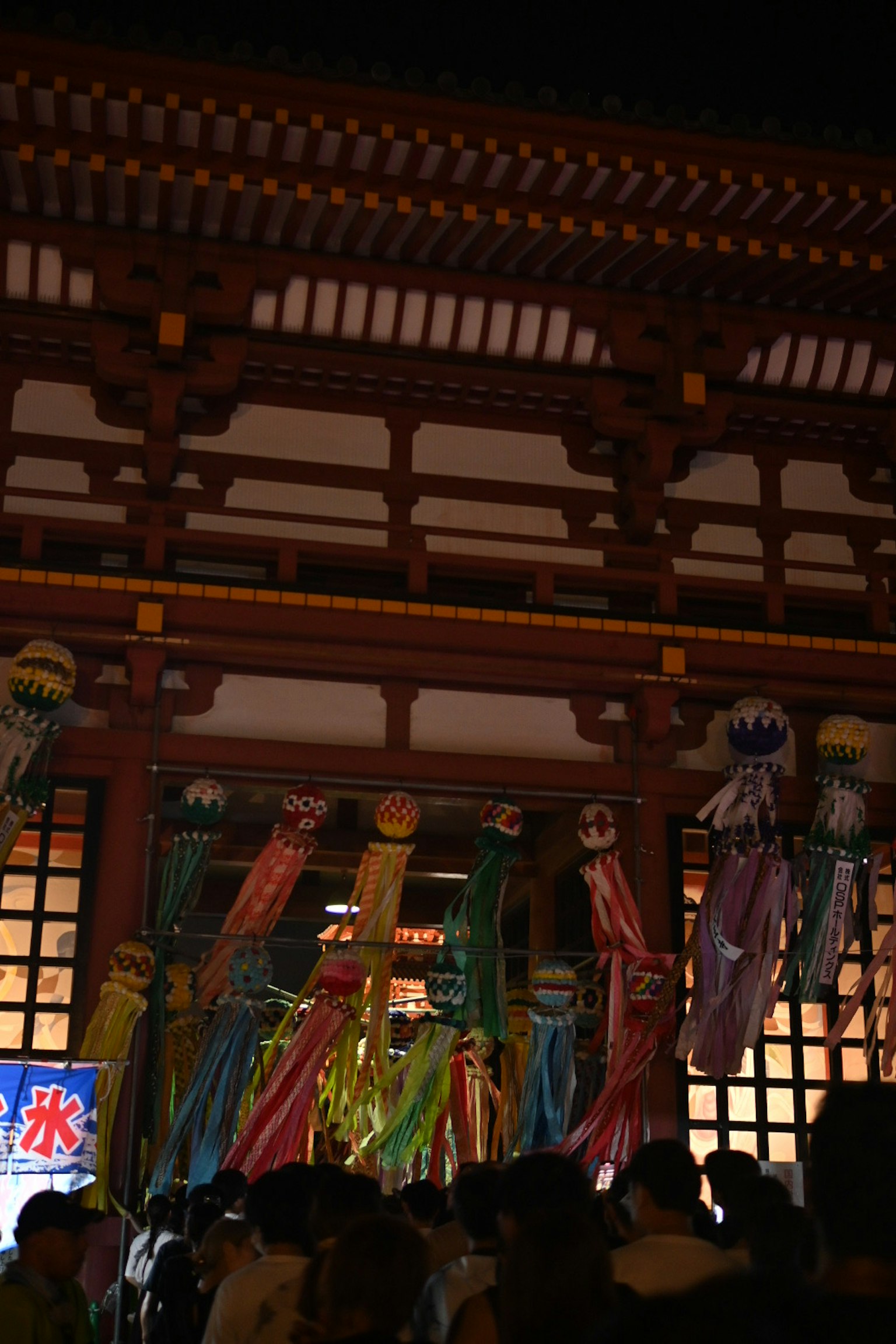 Entrance of a shrine at night with colorful decorations and festival atmosphere