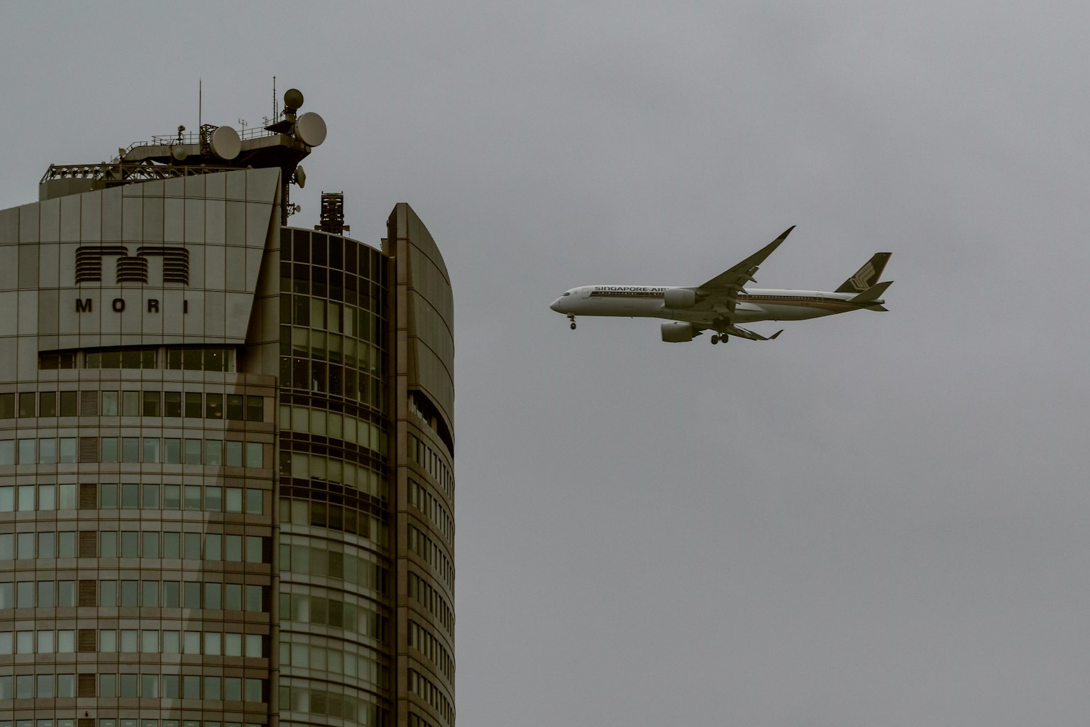 飛機在陰雲密布的天空下飛過摩天大樓