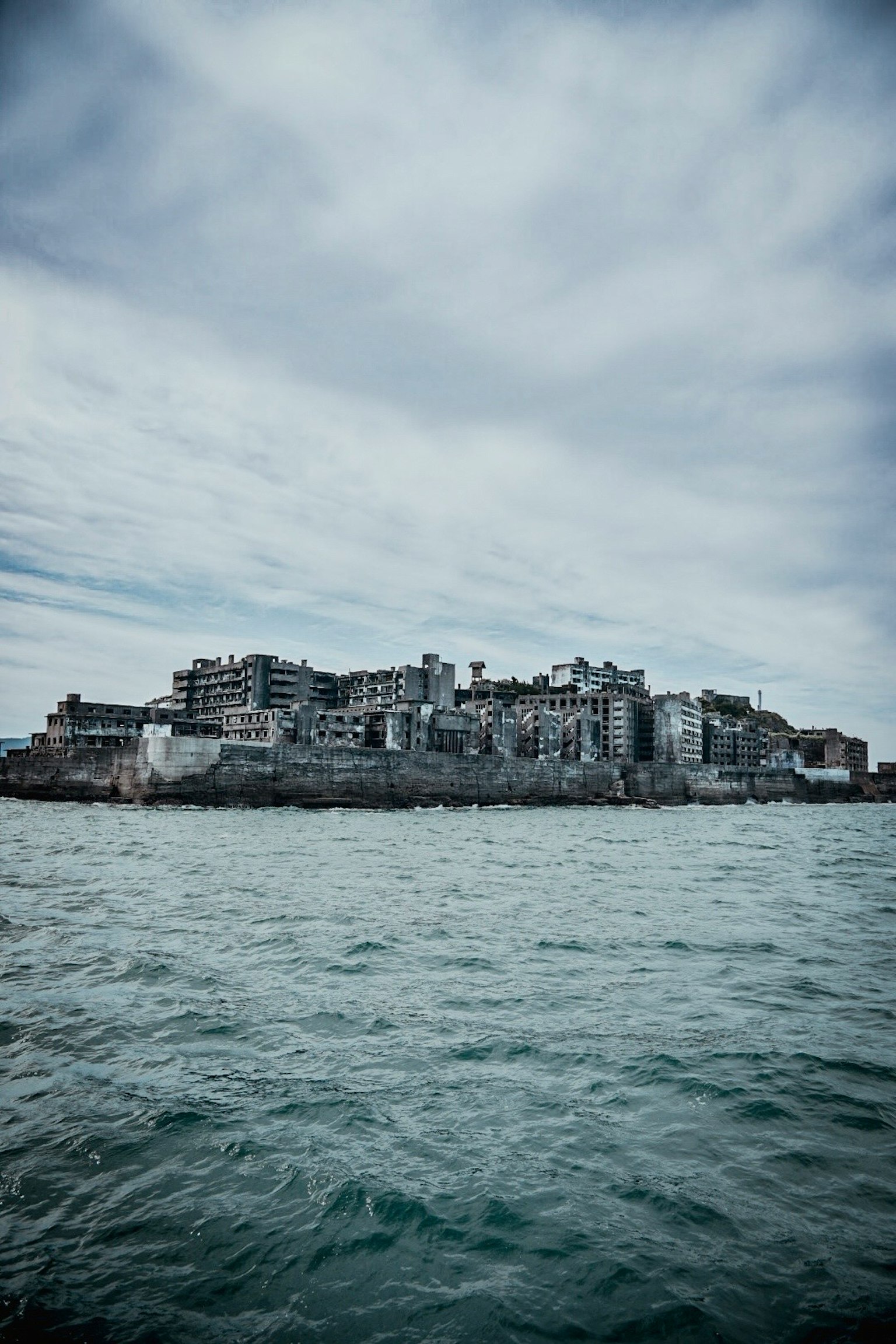 Edificios abandonados en una isla rocosa bajo un cielo nublado
