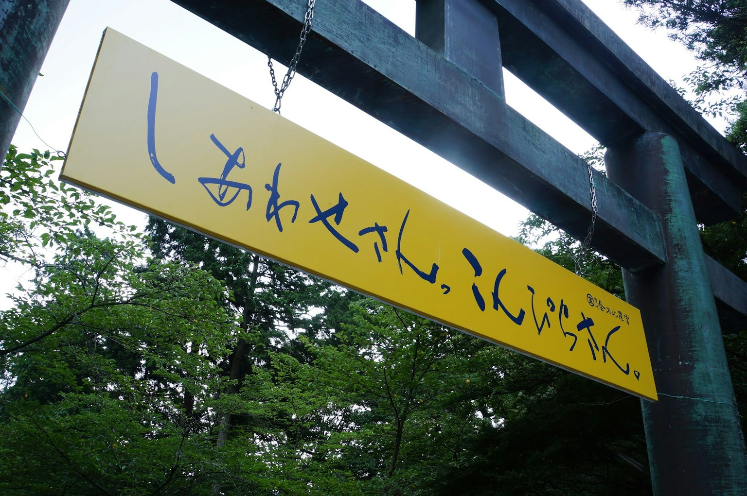 Panneau jaune avec du texte japonais dans un cadre verdoyant