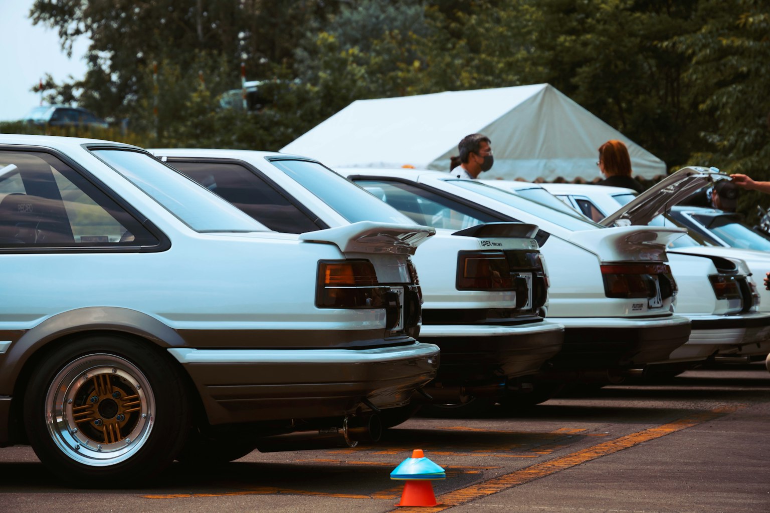 Dãy xe thể thao màu trắng với mọi người làm việc gần đó