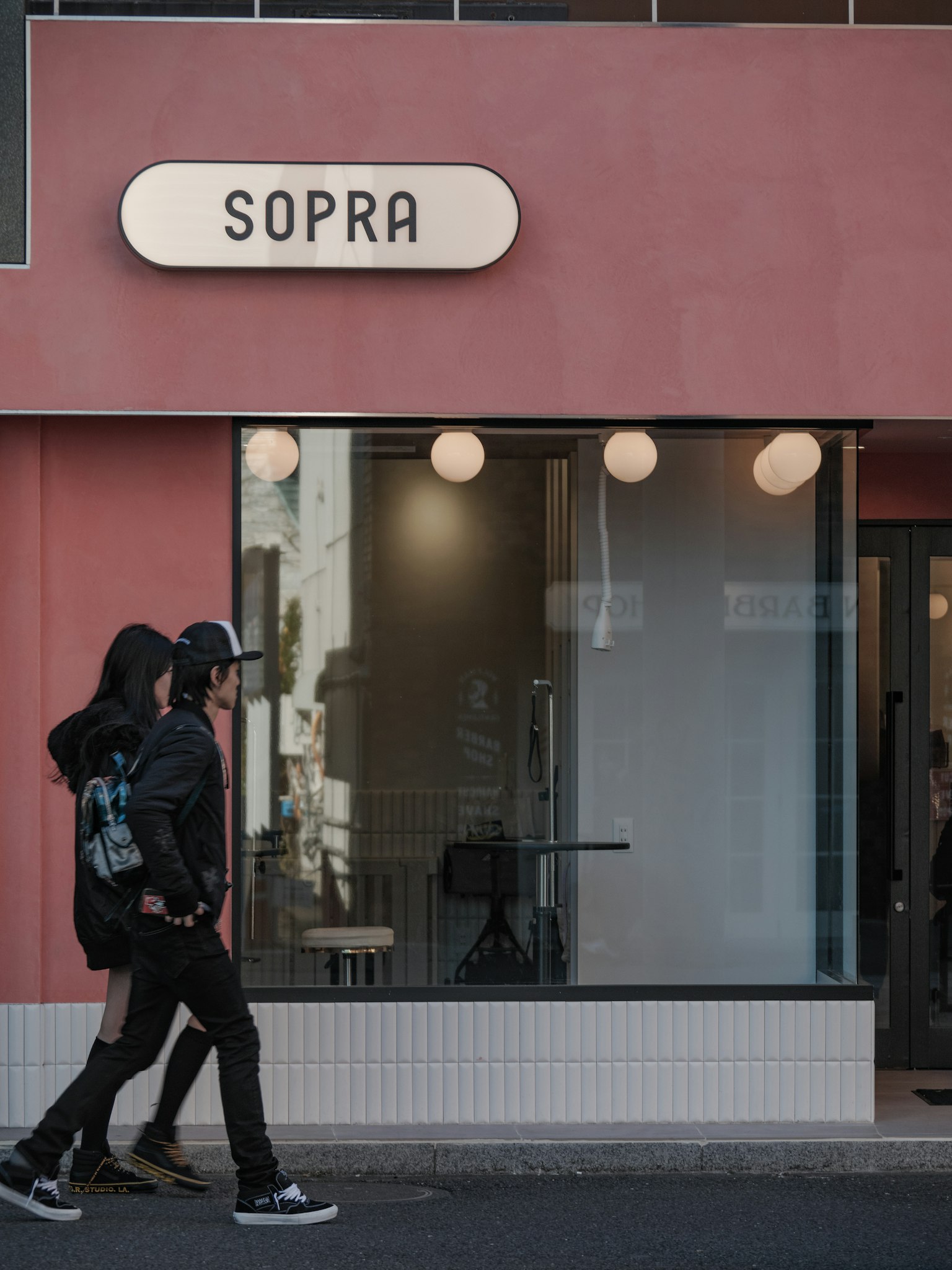 两个人在粉色外观的咖啡馆SOPRA前走