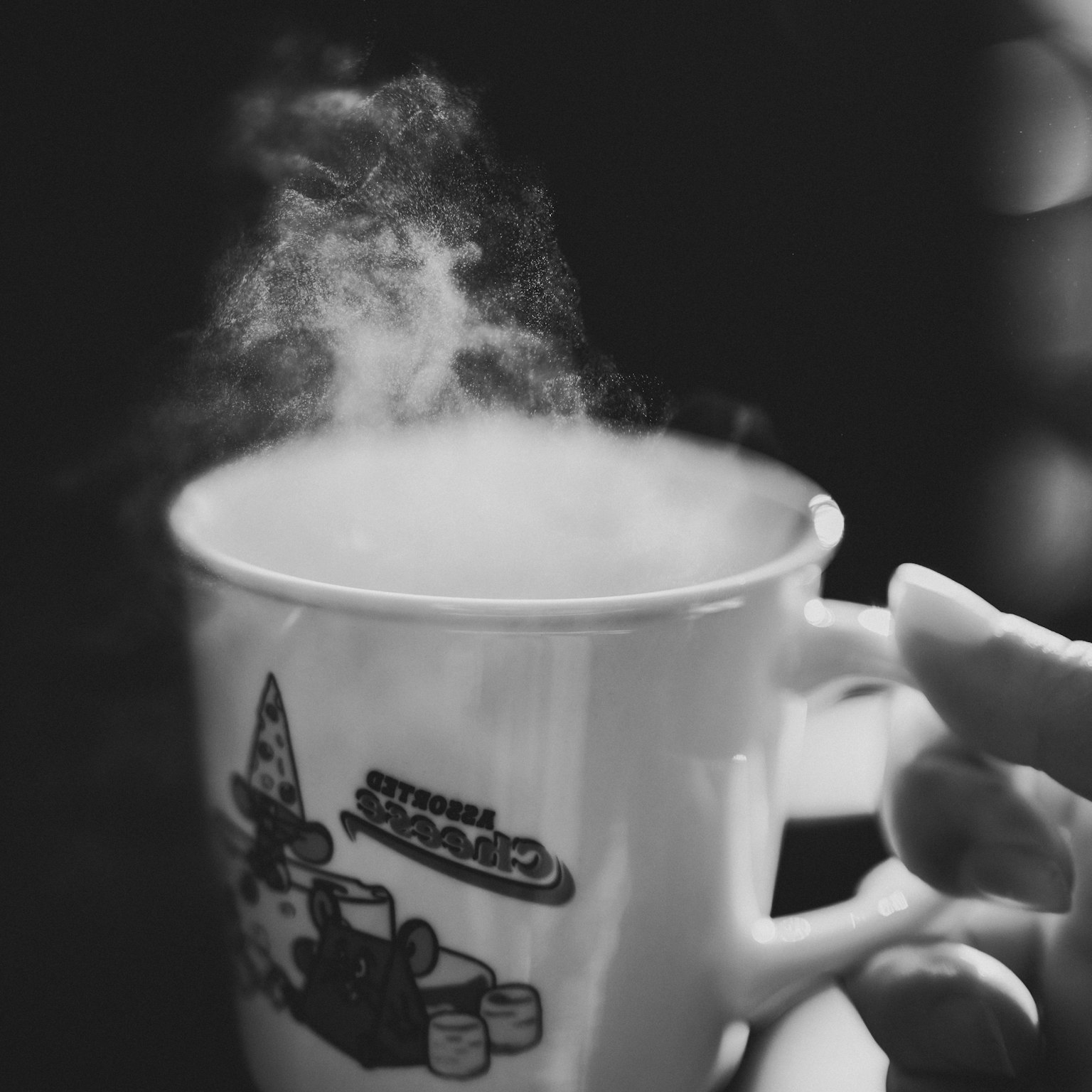 Image en noir et blanc d'une tasse fumante tenue par une main