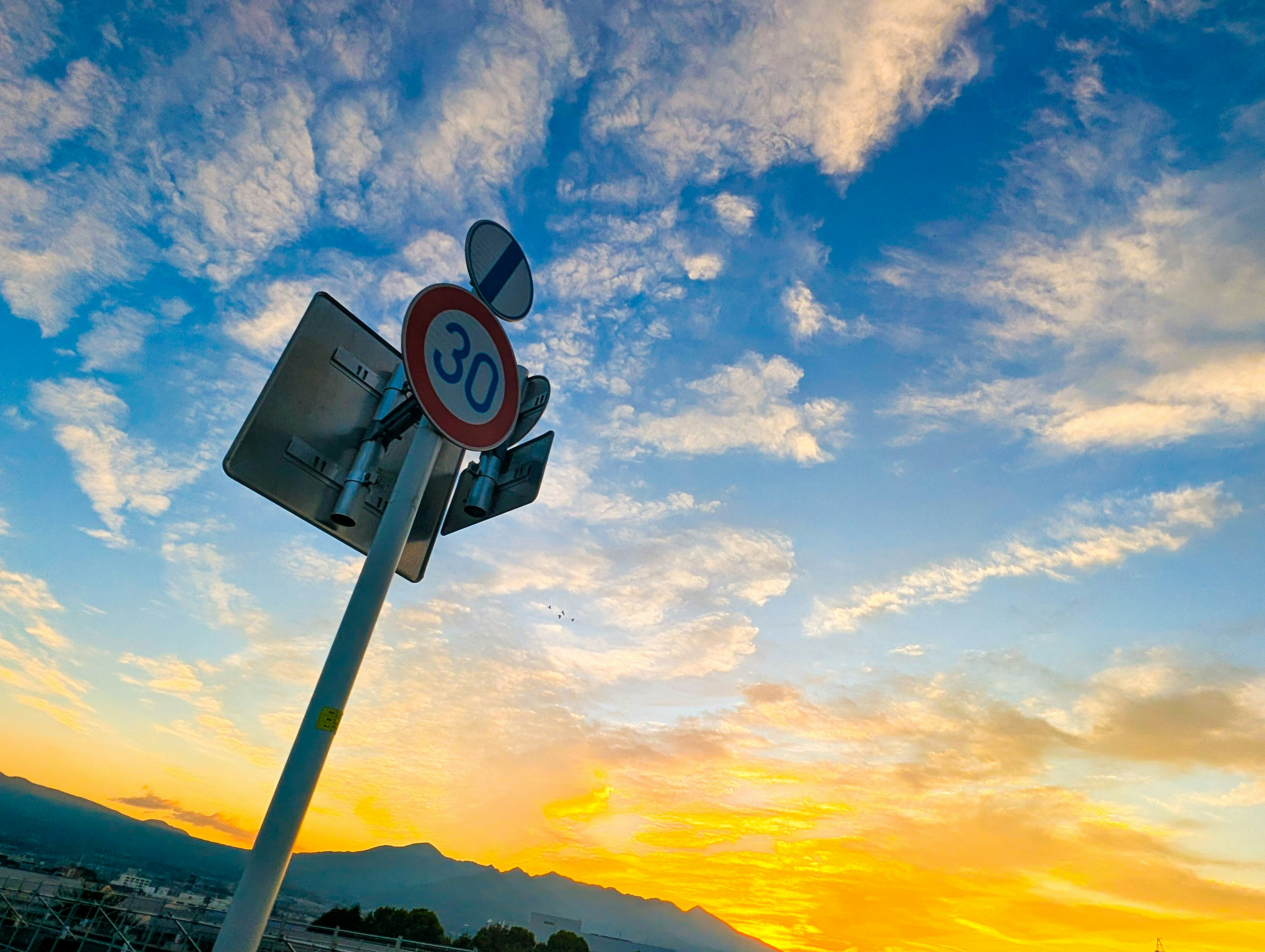 朝の道路標識と夕焼けの山並み
