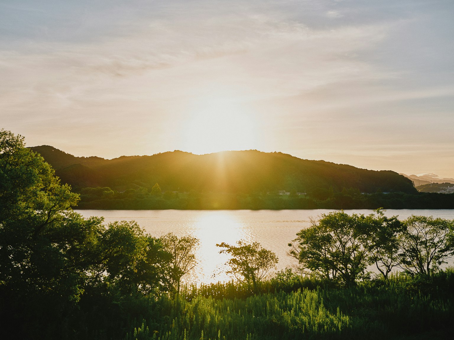 宁静的湖泊景观，夕阳在山后落下