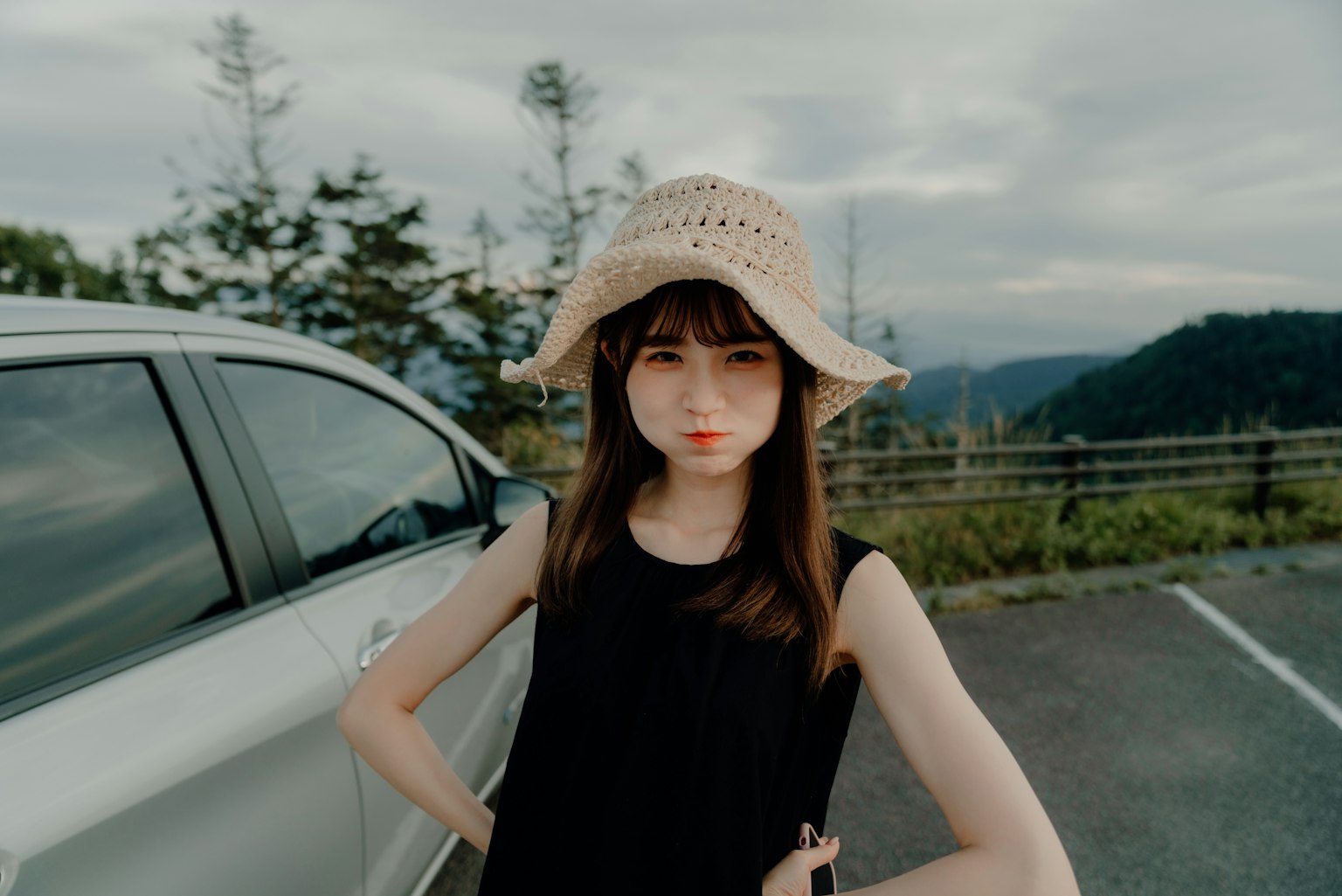 一位穿著黑色上衣和草帽的女性在戶外擺姿勢