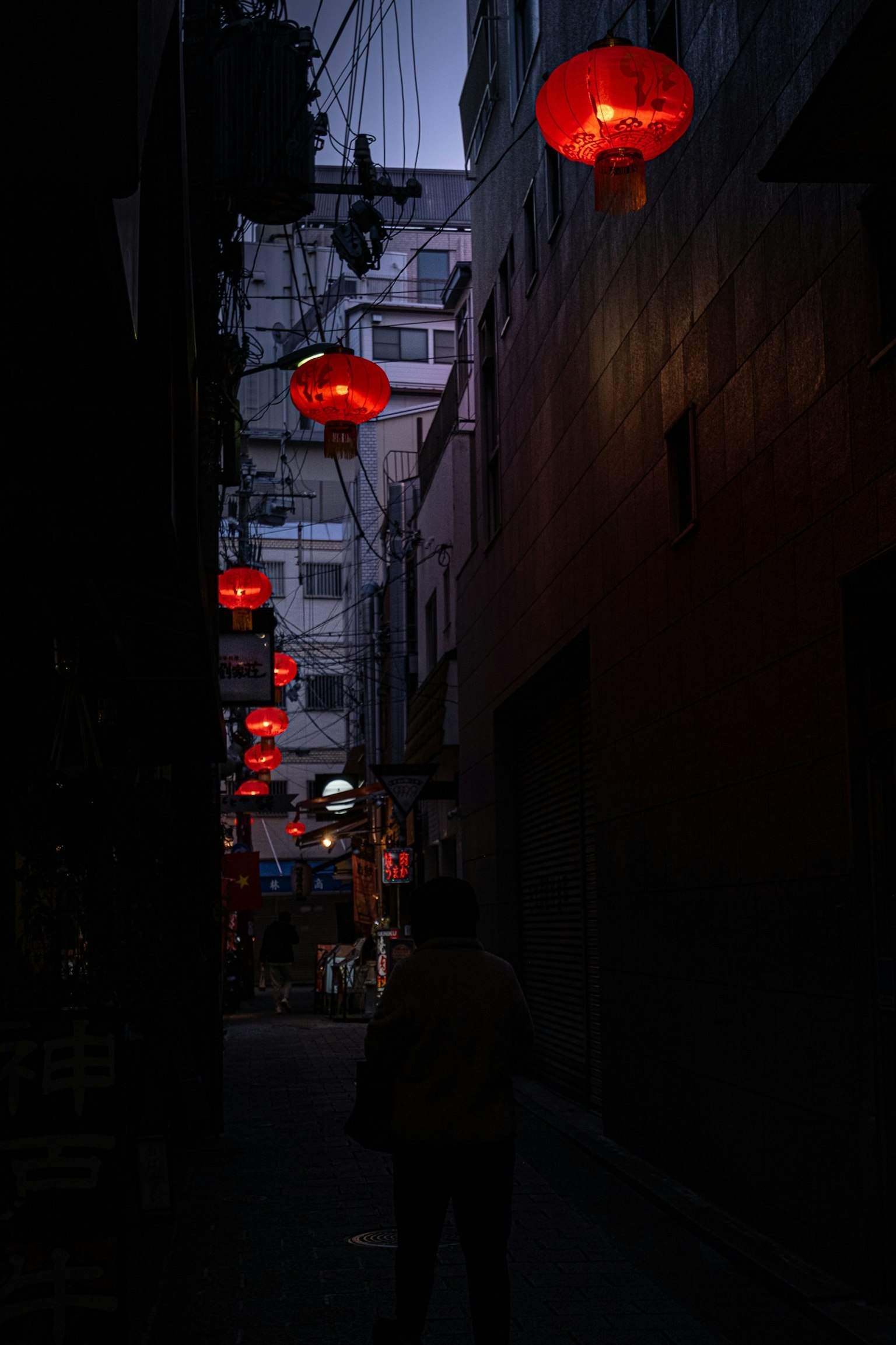 Calle stretta illuminata da lanterne rosse al crepuscolo