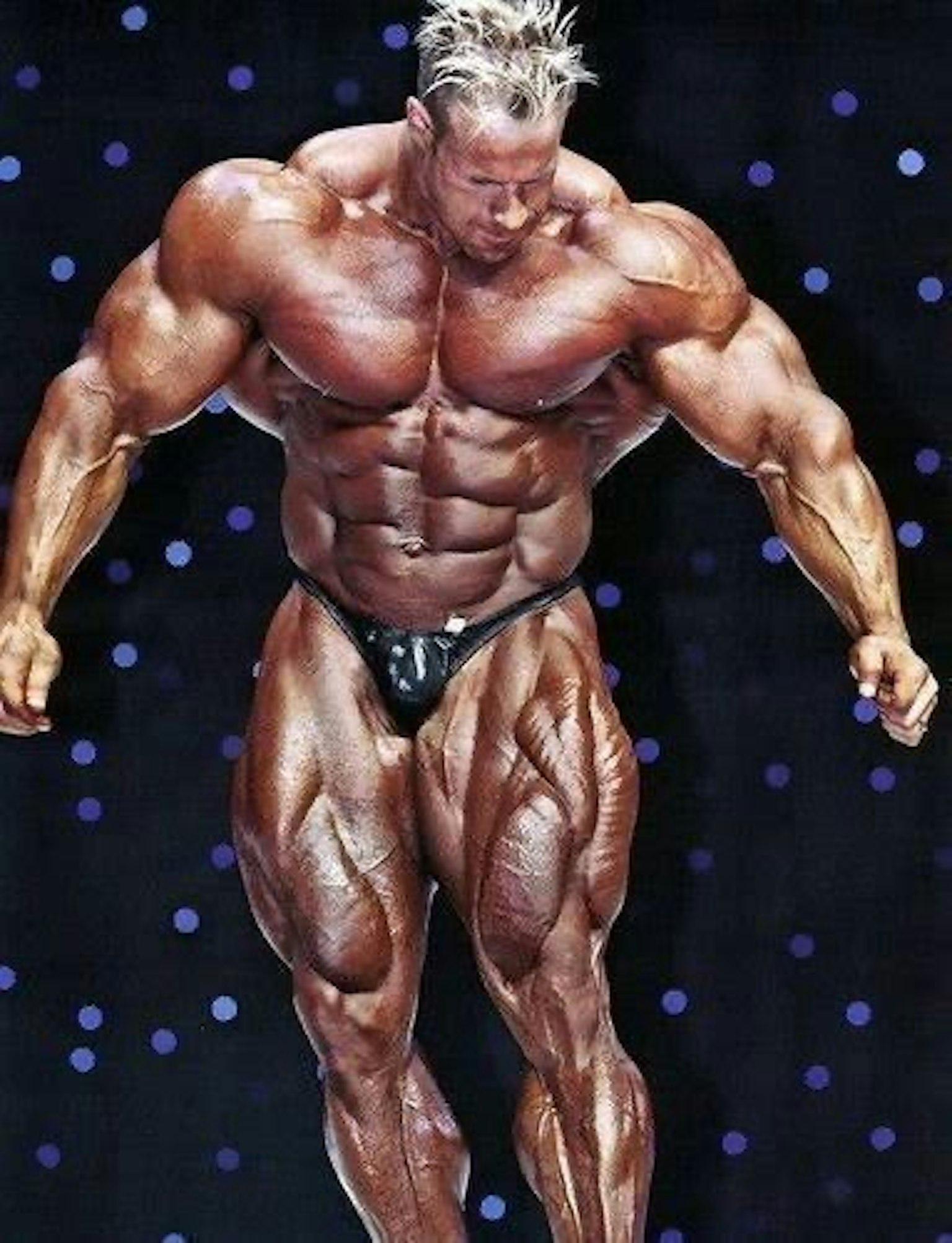 Muscular bodybuilder posing on stage with a focused expression