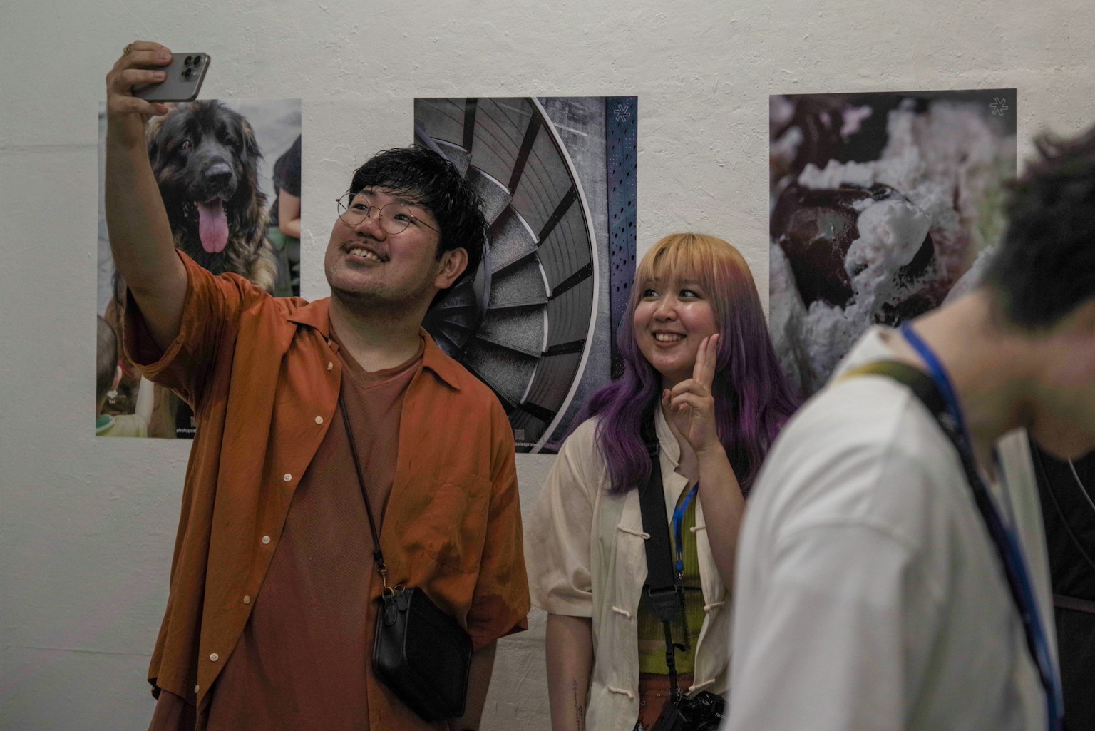 Giovane uomo e donna che scattano selfie in una galleria d'arte con fotografie sulle pareti